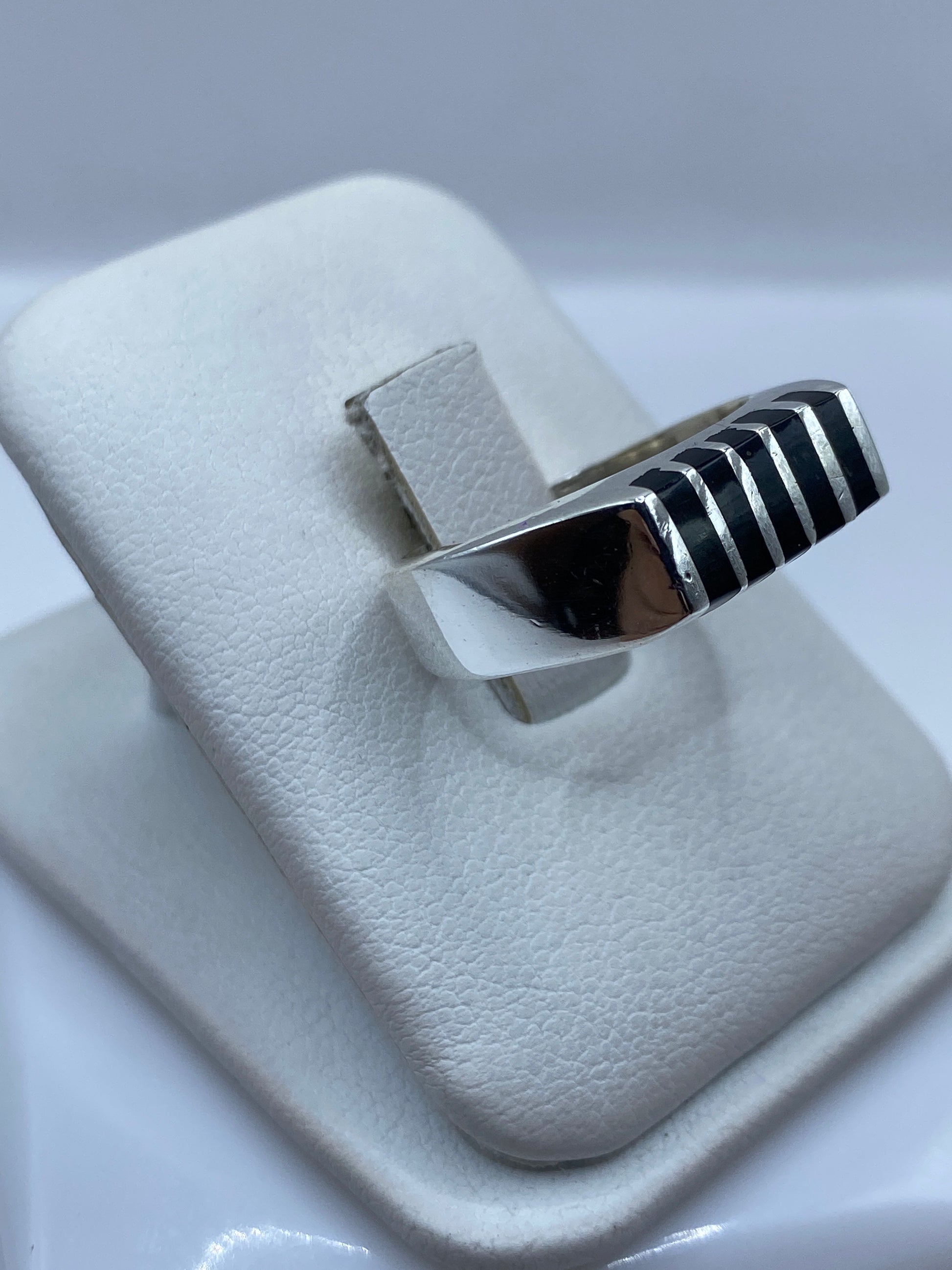 Anillo unisex de ónix y plata pulido a mano, vista lateral sobre dedo, luz natural