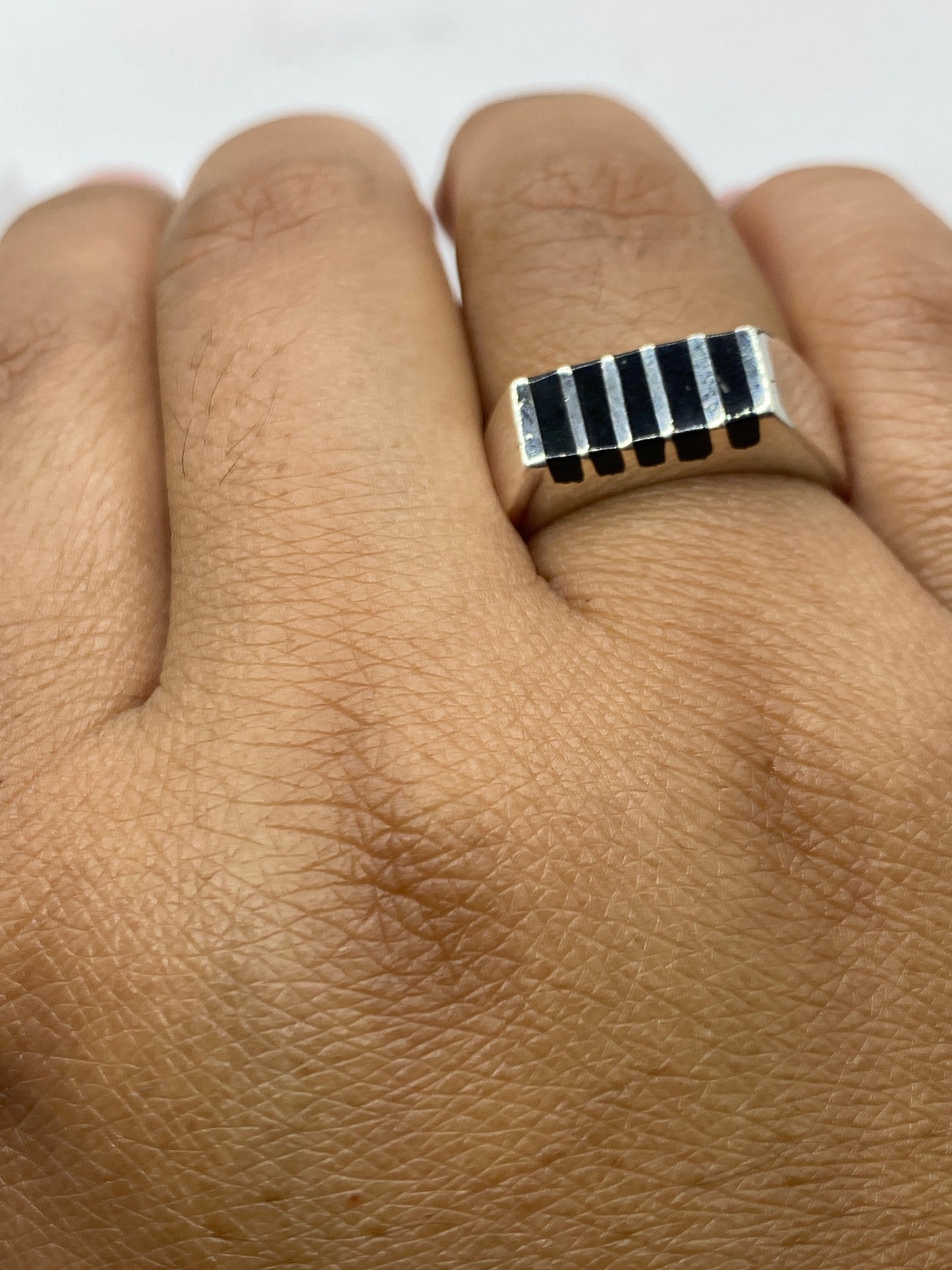Anillo de ónix y plata en mano descansando, tamaño y presencia reales del diseño banda ancha