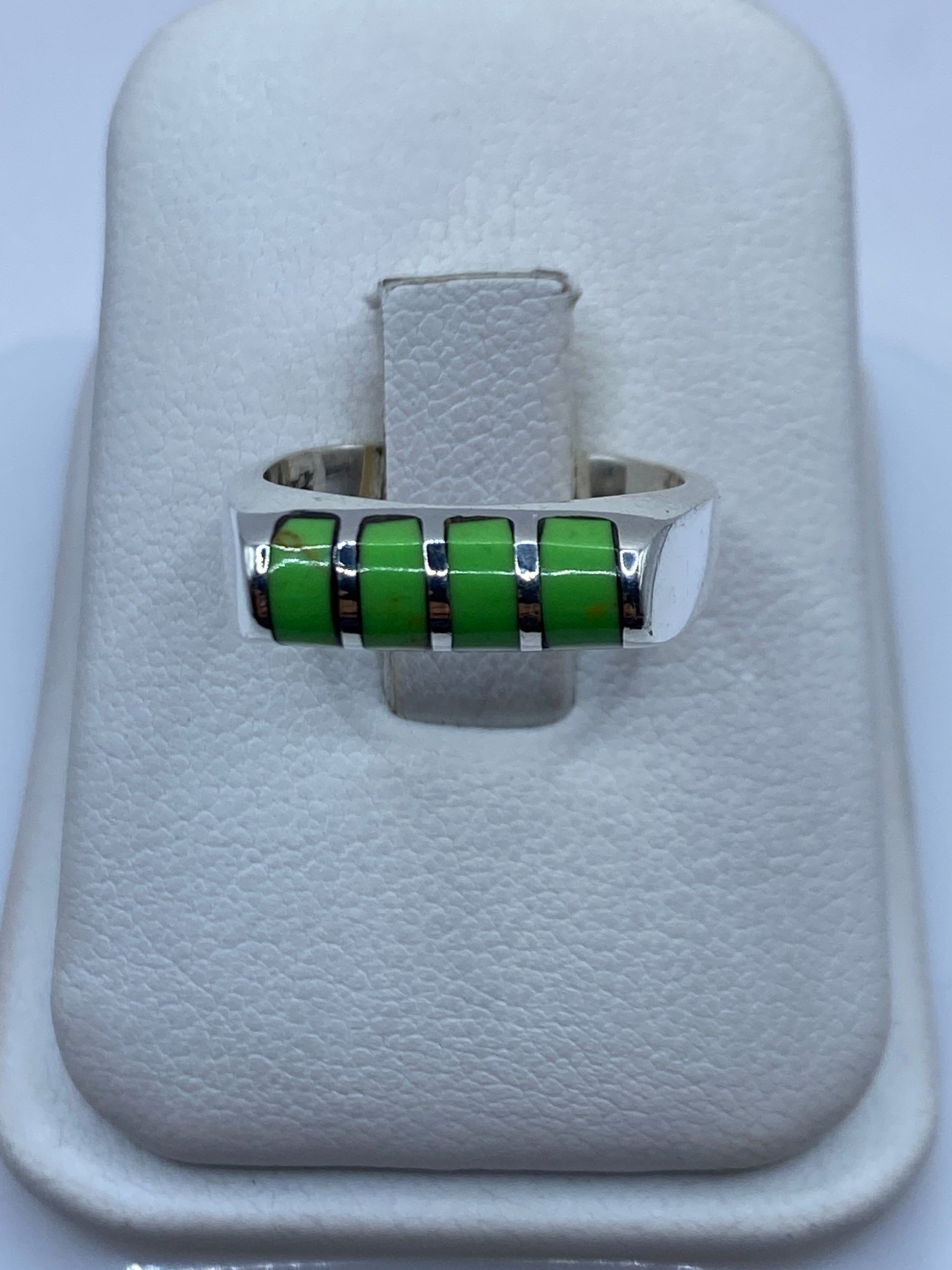 Anillo giratorio de plata con piedras verdes en una mano, mostrando el movimiento fluido