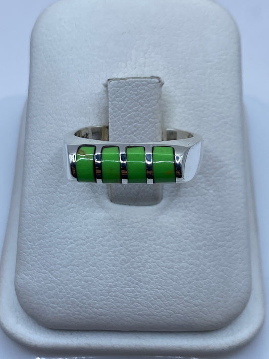 Anillo giratorio de plata con piedras verdes en una mano, mostrando el movimiento fluido