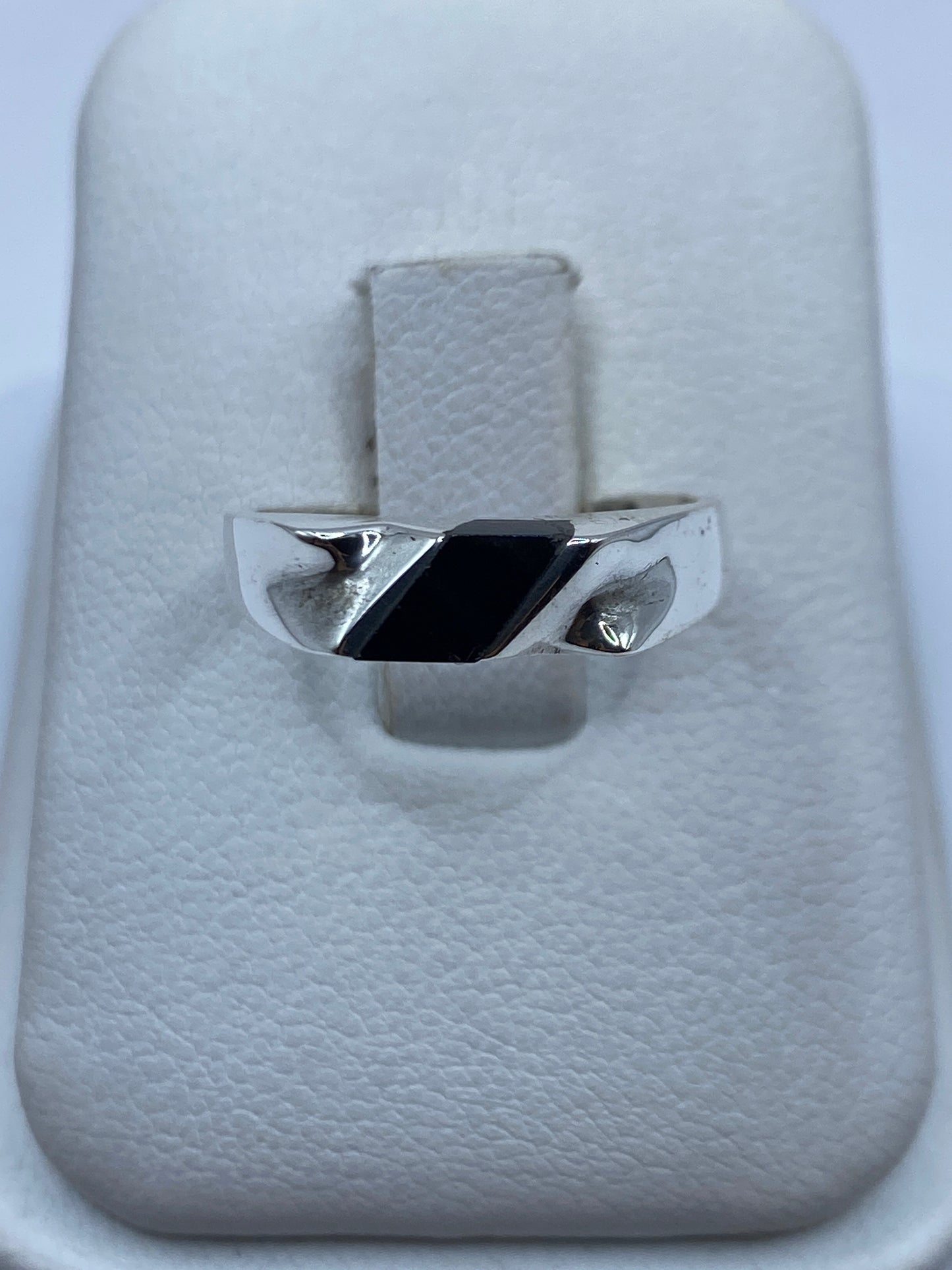Anillo de plata con ónix negro pulido sobre estuche blanco, vista frontal