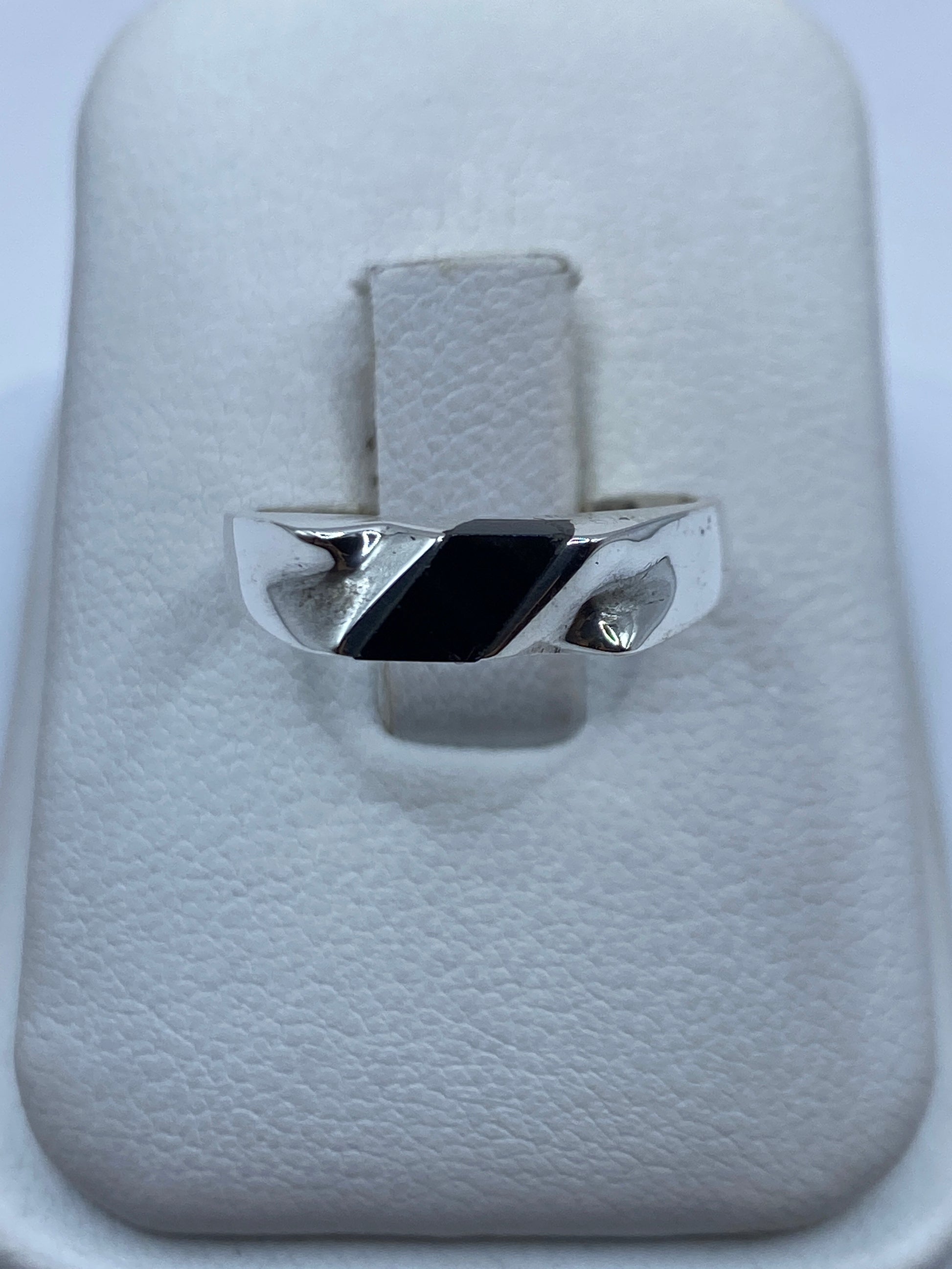 Anillo de plata con ónix negro pulido sobre estuche blanco, vista frontal