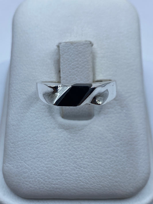 Anillo de plata con ónix negro pulido sobre estuche blanco, vista frontal