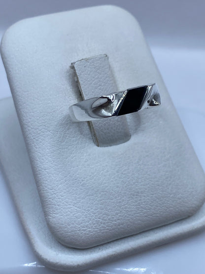 Anillo minimalista plata-ónix en la mano, mostrando el acabado liso y elegante