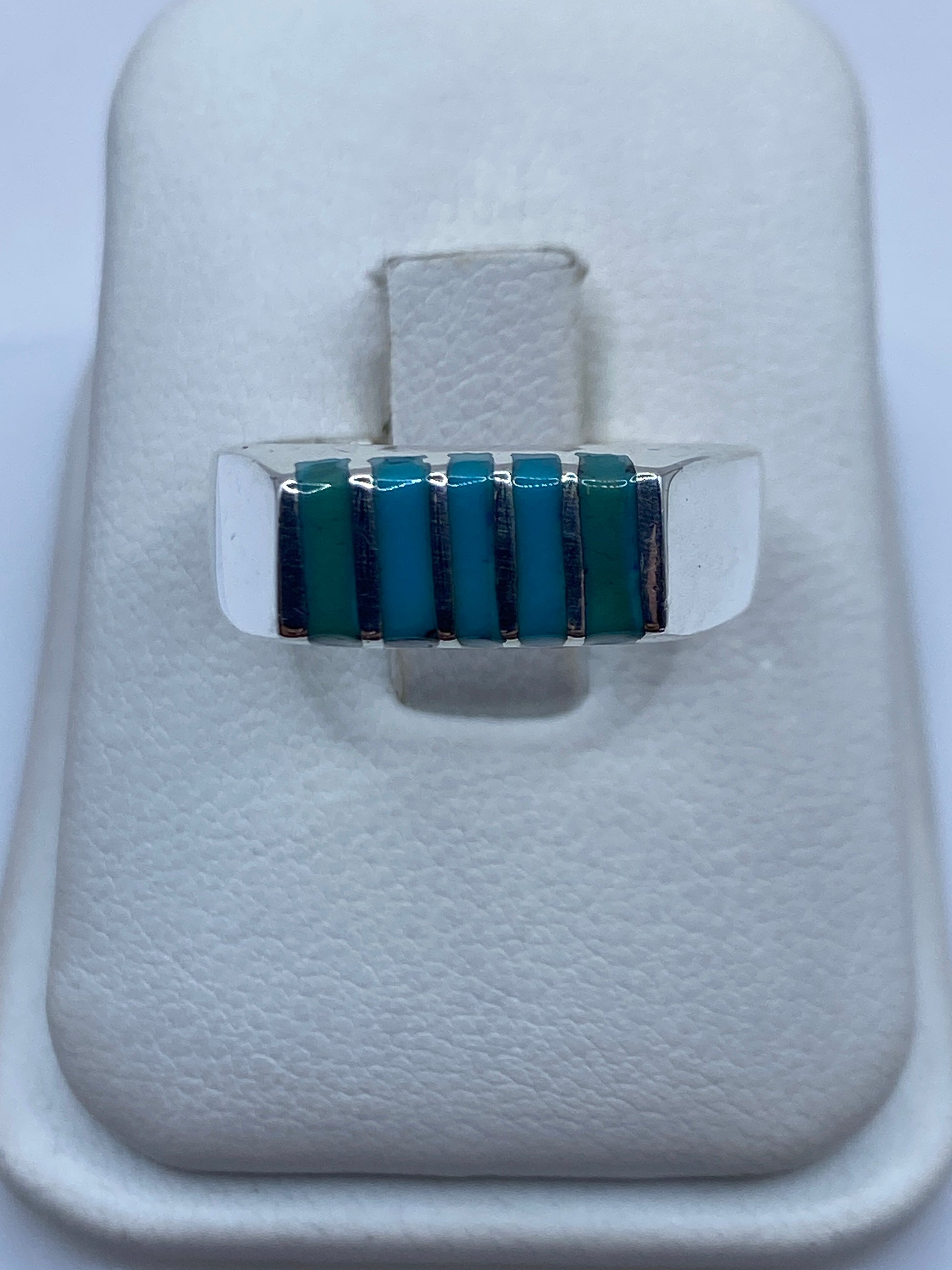 Anillo de plata con bandas escalonadas y piedras azul cielo, visto de frente sobre fondo blanco