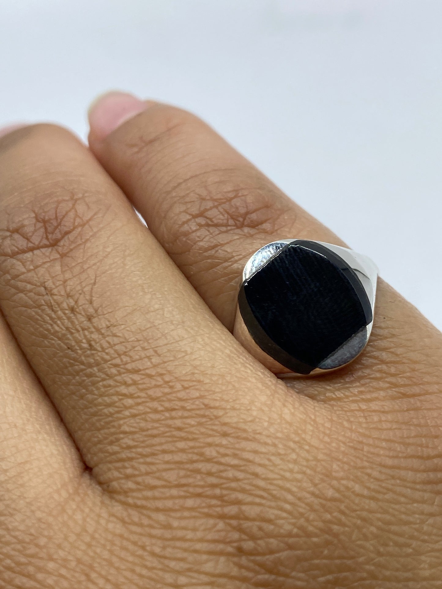 Anillo de plata con ónix negro en mano mostrando el pulido perfecto de la piedra