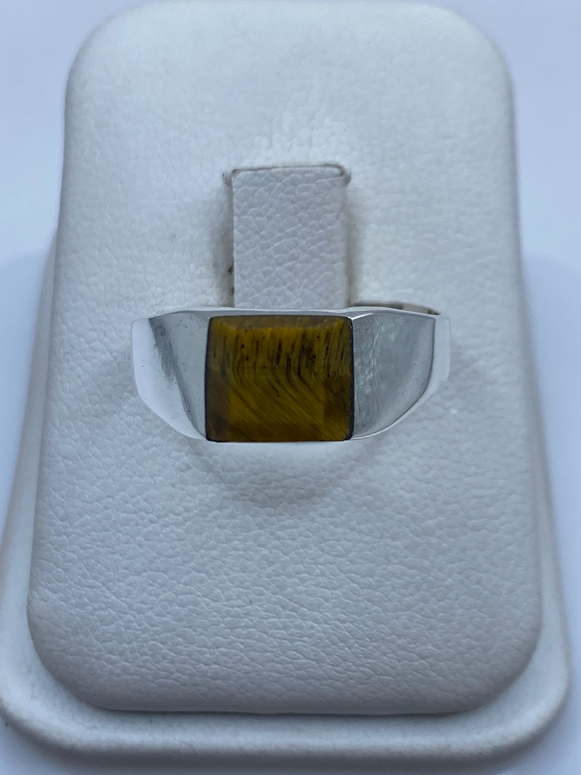 Anillo de plata minimalista con piedra natural café en la mano de una persona