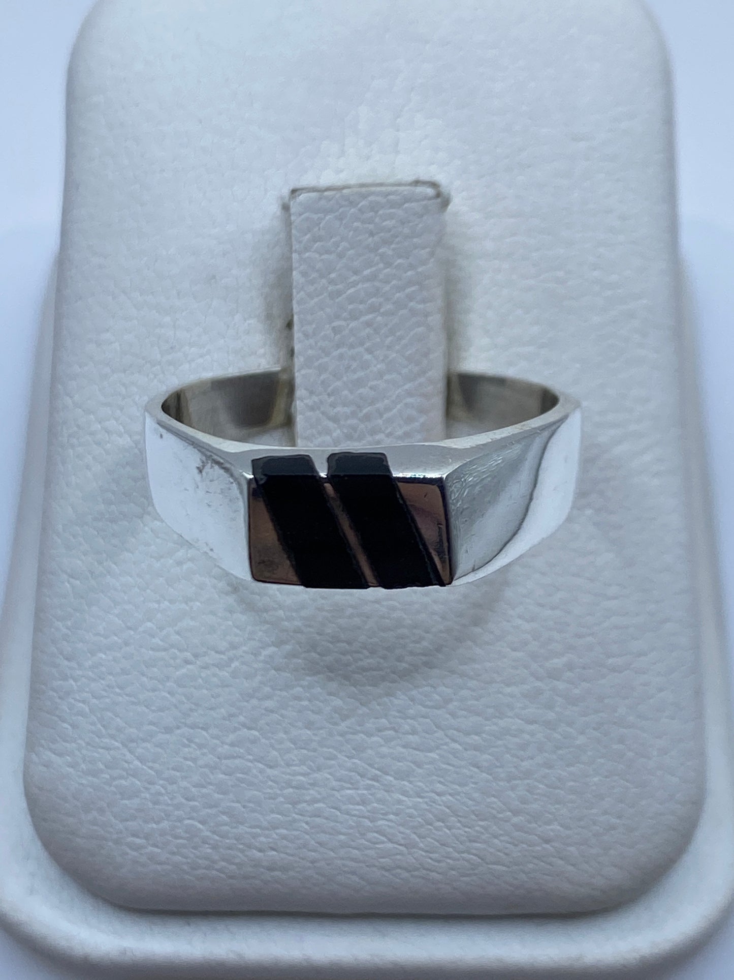 Anillo de plata con ónix negro en la mano de una persona, vista frontal