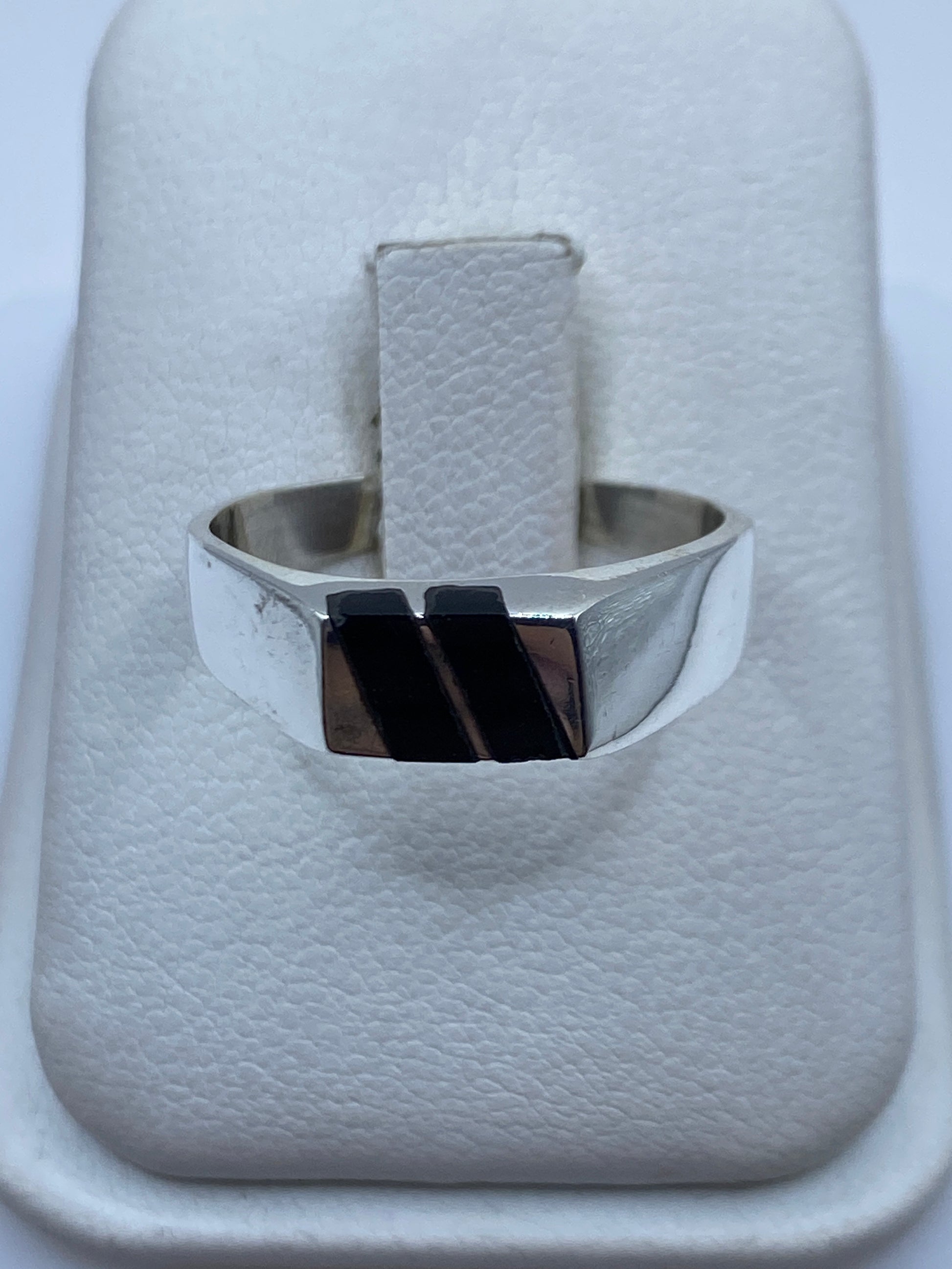 Anillo de plata con ónix negro en la mano de una persona, vista frontal