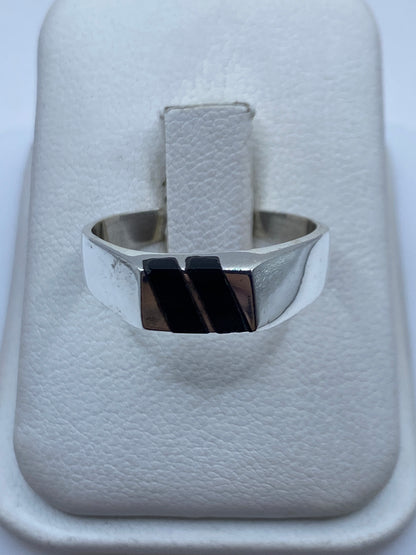 Anillo de plata con ónix negro en la mano de una persona, vista frontal