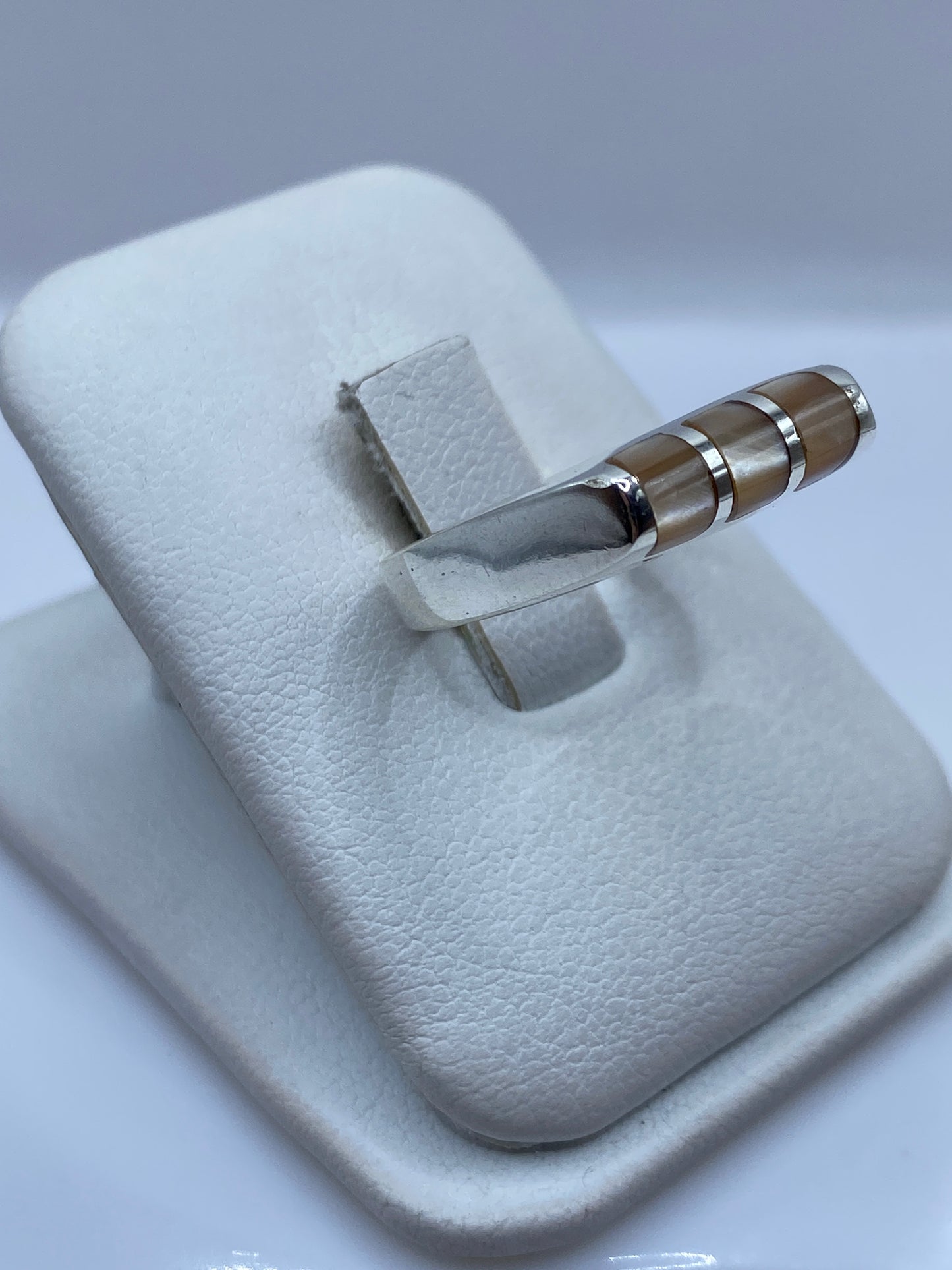 Anillo con piedra café en tonos cálidos, vista lateral en mano de mujer
