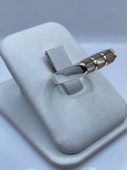 Anillo con piedra café en tonos cálidos, vista lateral en mano de mujer