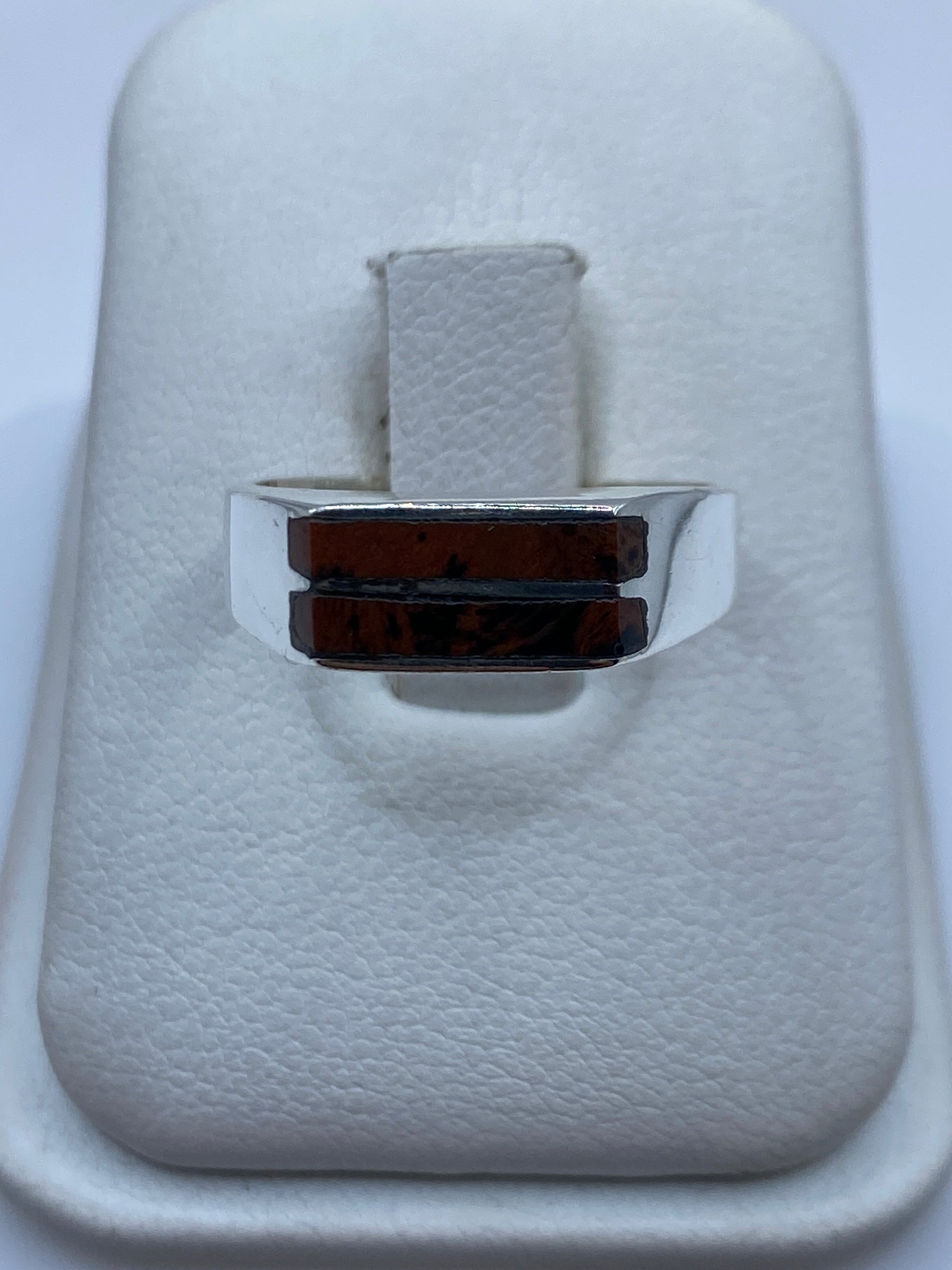Anillo de plata con piedra café sobre fondo blanco, vista de frente