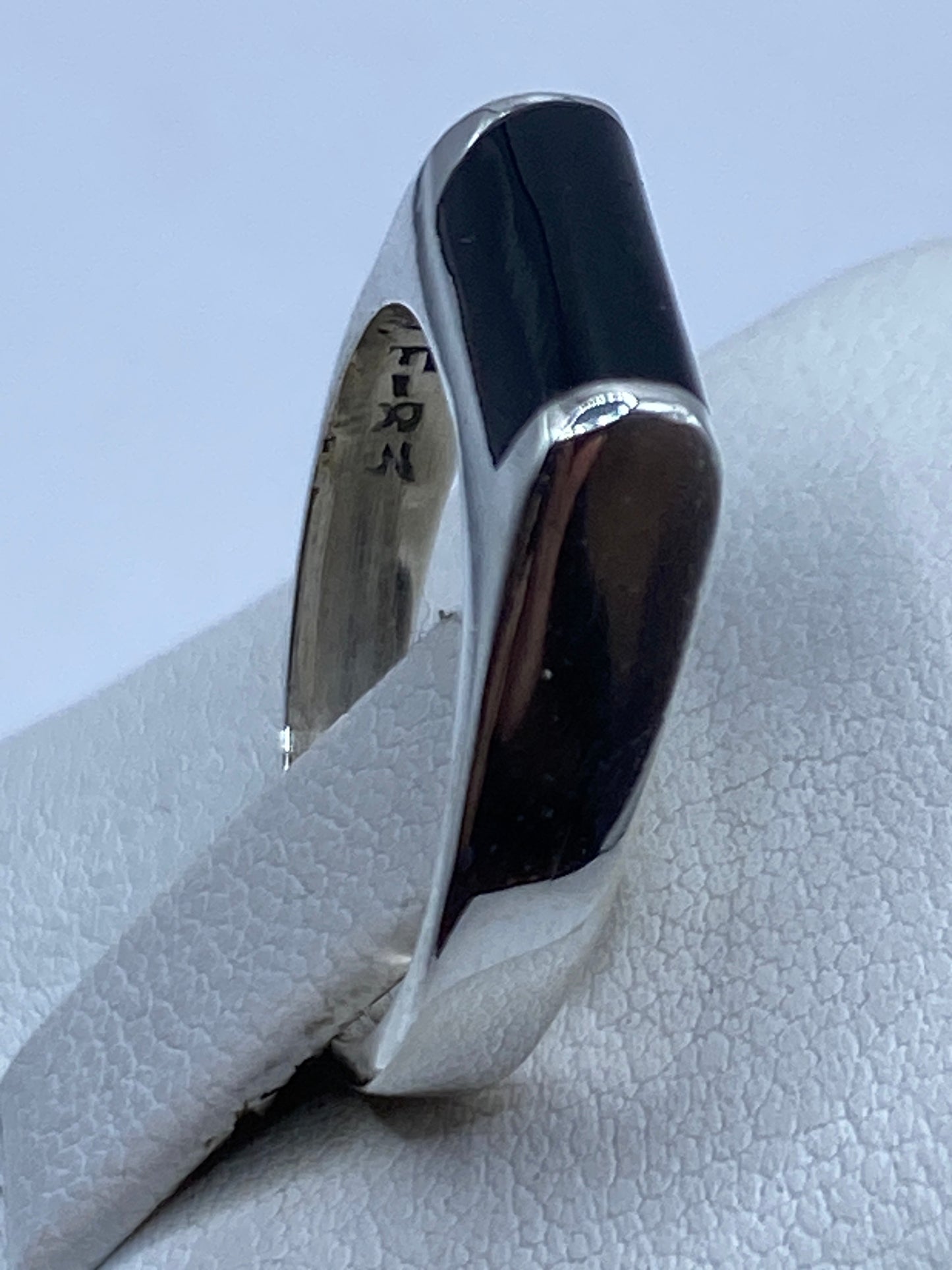 Anillo de ónix rectangular visto desde arriba sobre algodón blanco
