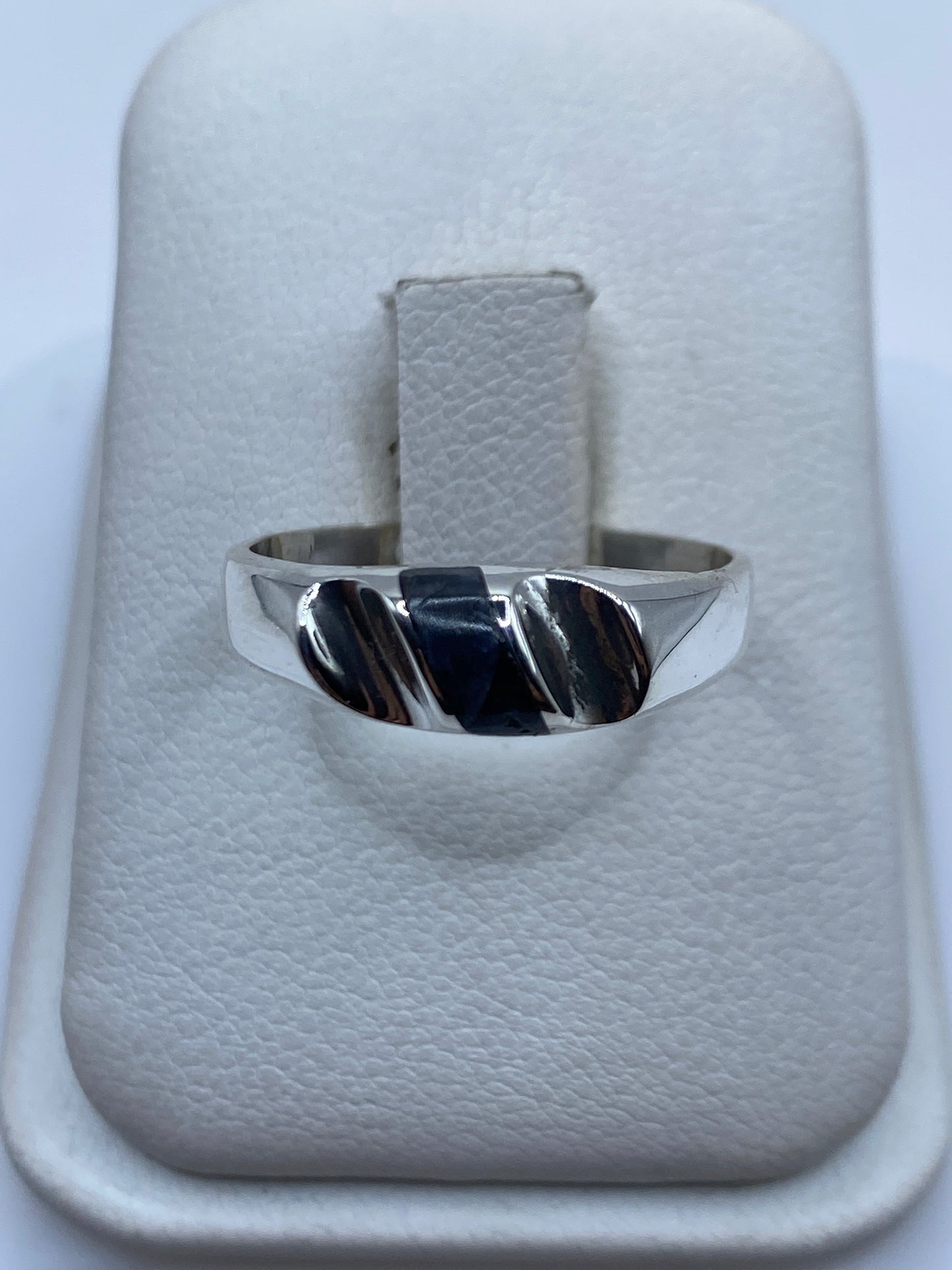 Anillo de plata con onix negro sobre almohada blanca, vista frontal del diseño minimalista