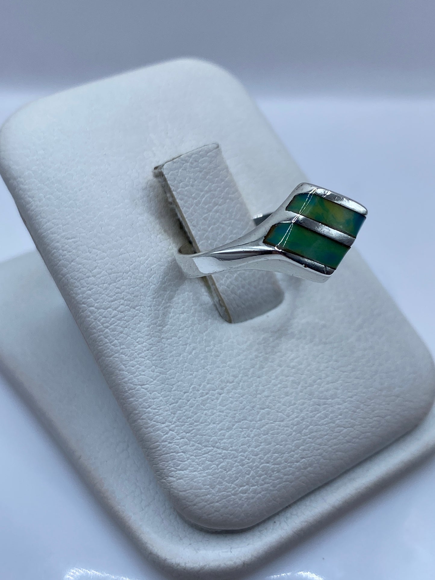 Vista frontal del anillo minimalista con piedra verde teal en degradé