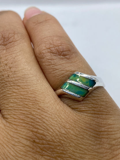 Anillo en dedo mostrando los tonos verdes y azules naturales de la piedra