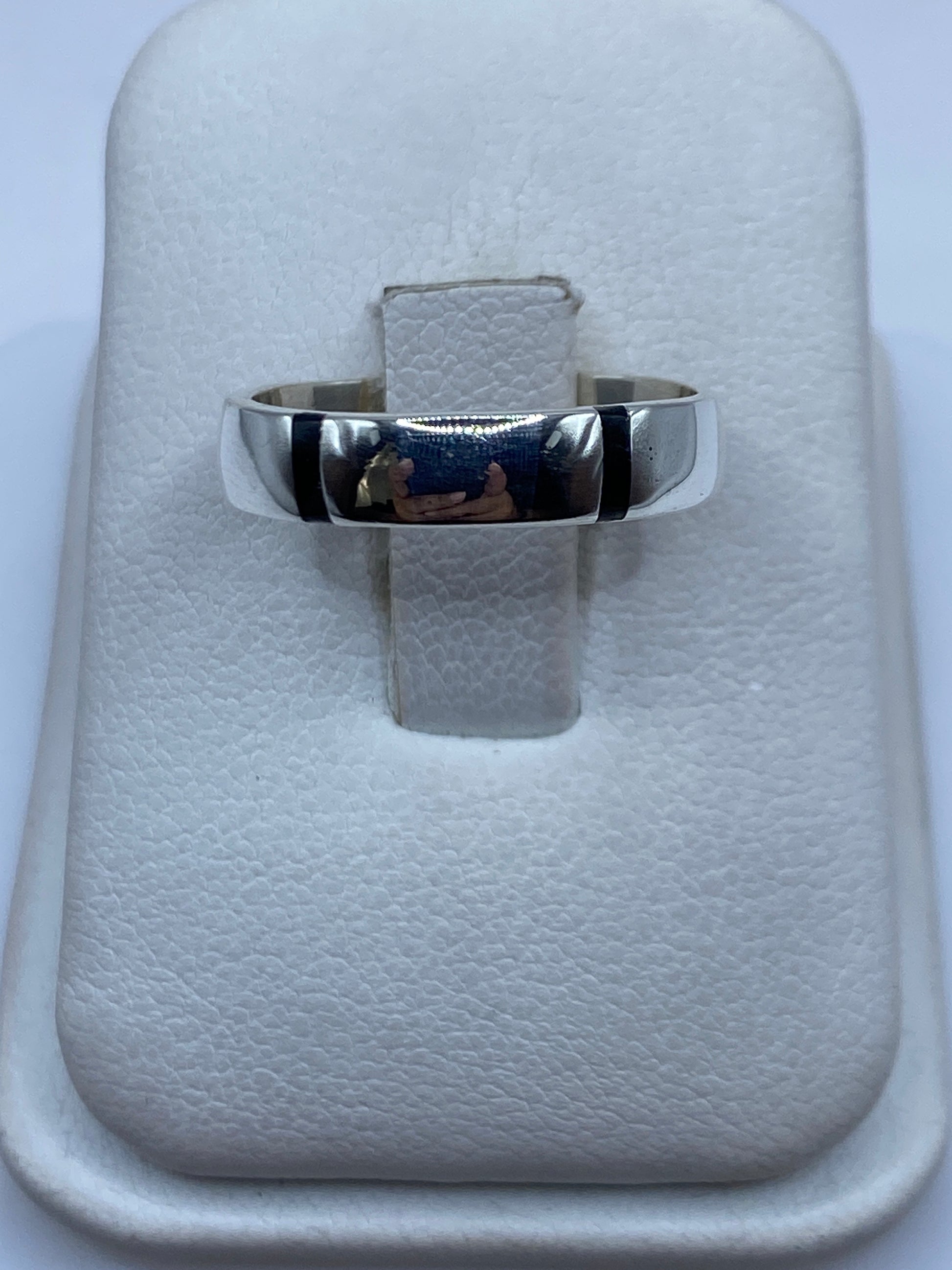 Anillo de plata con ónix negro pulido sobre estuche blanco, vista frontal