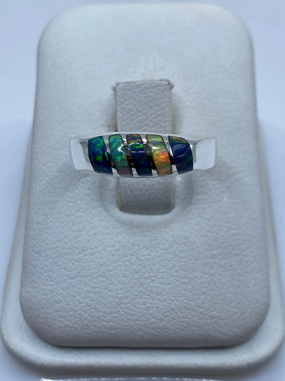 Anillo de plata con ópalo de fuego multicolor mostrando juego de verdes, azules y naranjas