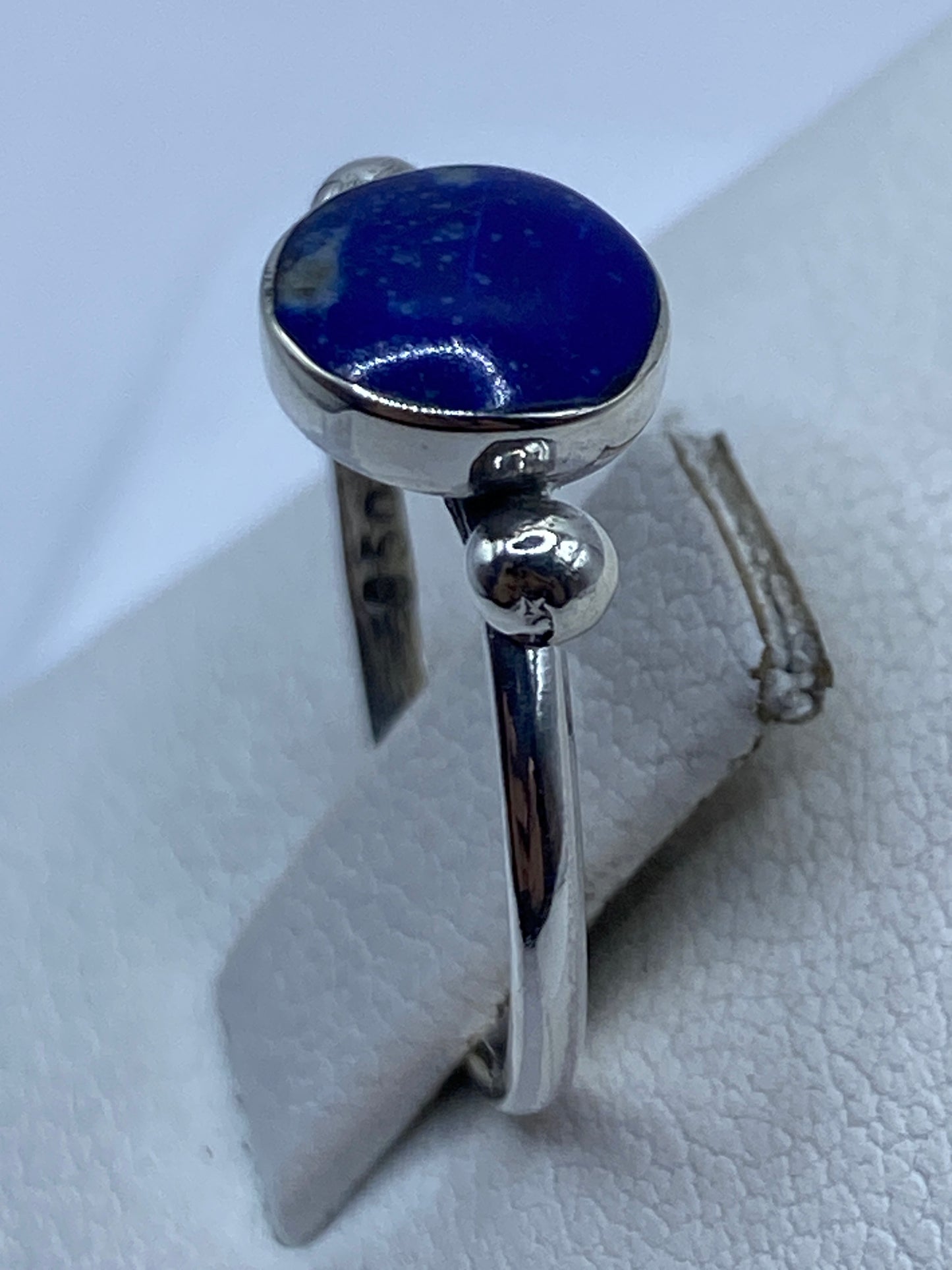 Anillo solitario en dedo de mujer, mostrando el color azul natural de la piedra