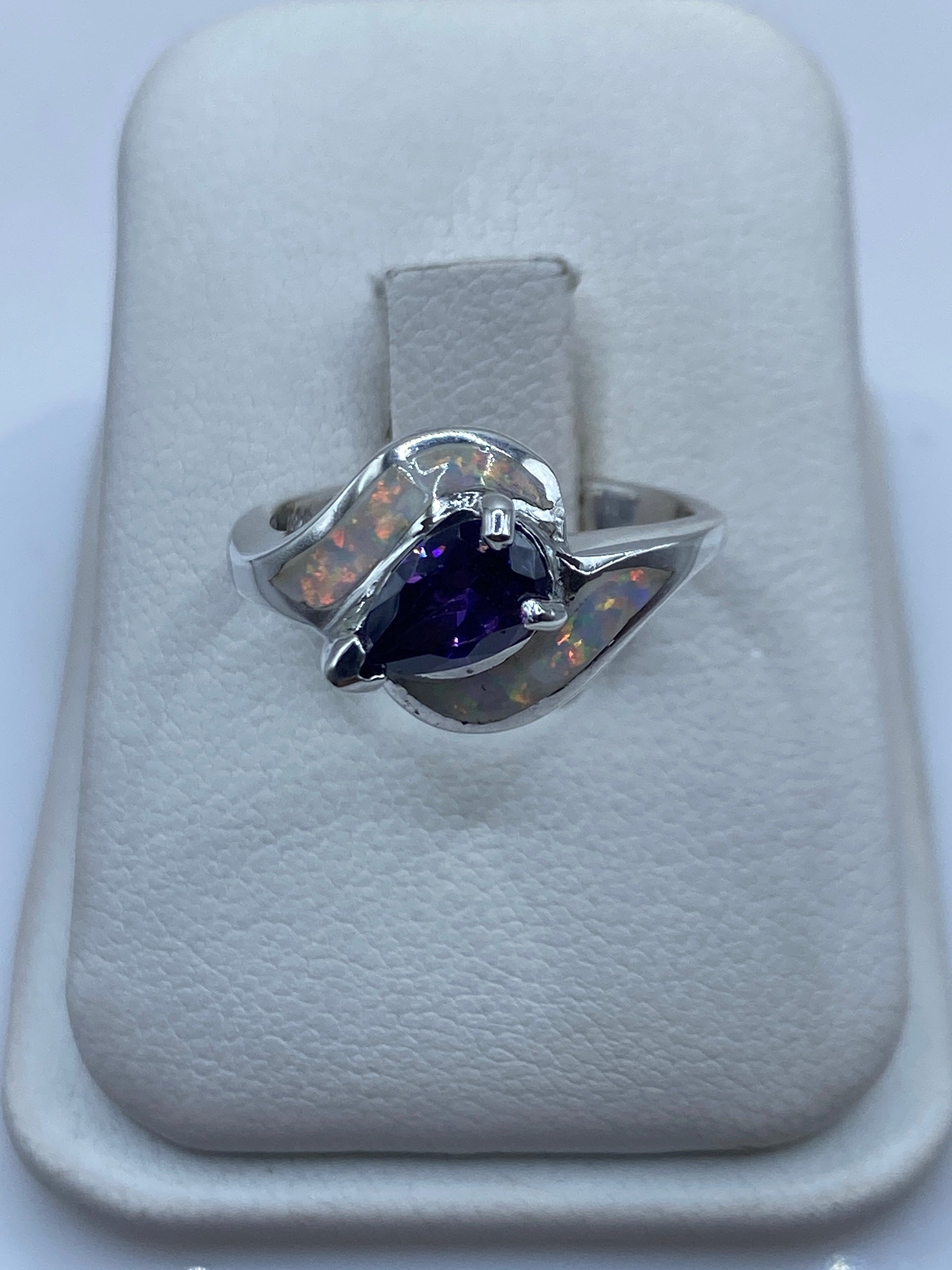 Anillo de plata con ópalo de fuego natural en tonos naranja y verde, abrazo asimétrico en mano de mujer