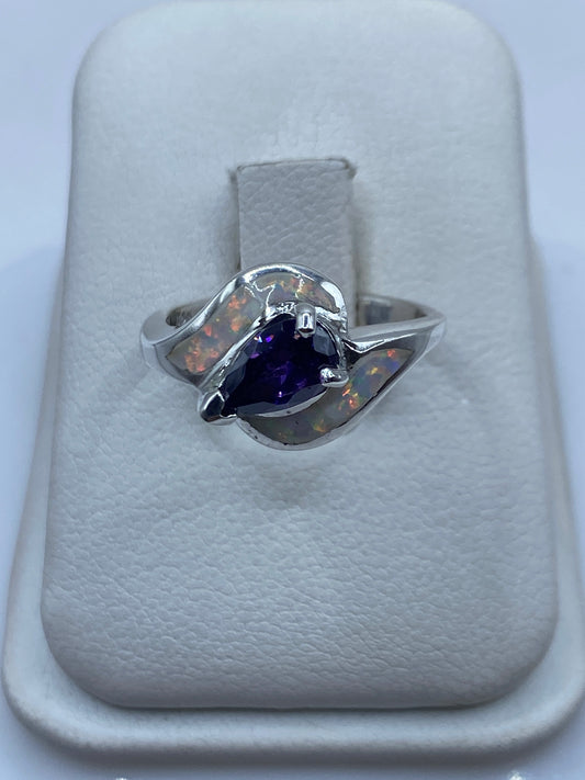 Anillo de plata con ópalo de fuego natural en tonos naranja y verde, abrazo asimétrico en mano de mujer