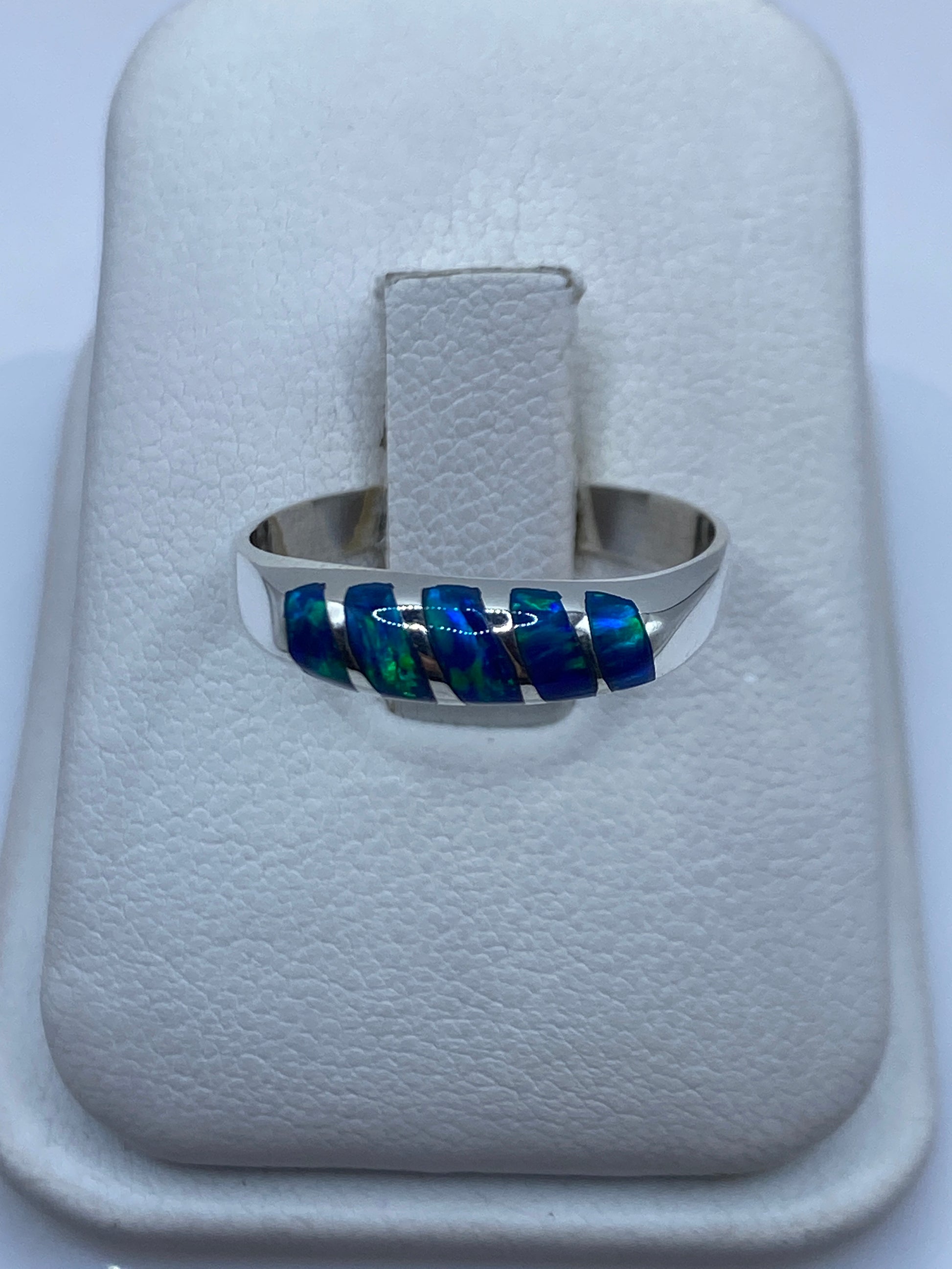 Anillo de plata con ópalo de fuego azul sobre estuche blanco, vista frontal