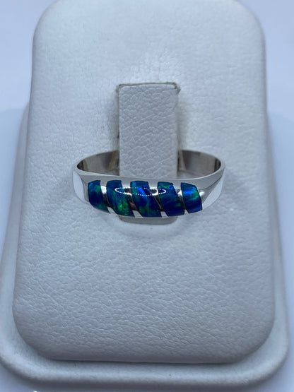 Anillo de plata con ópalo de fuego azul sobre estuche blanco, vista frontal