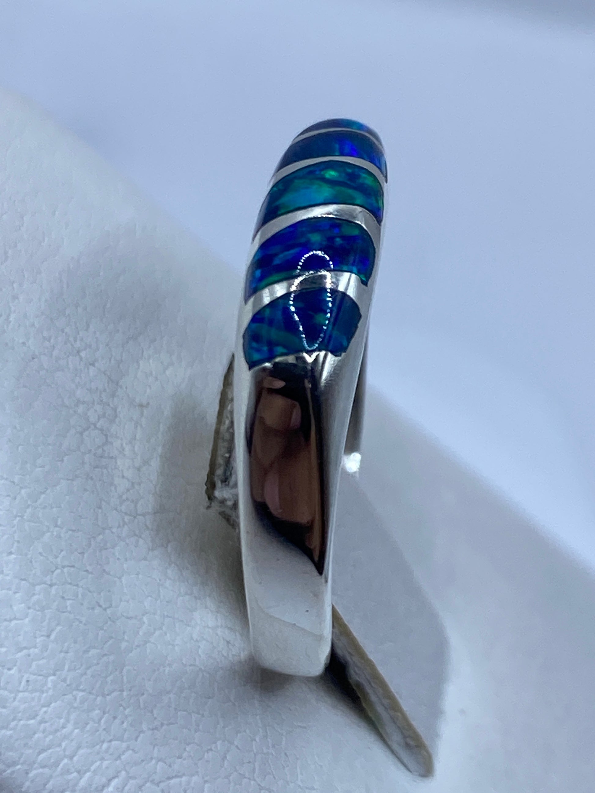 Ópalo de fuego azul en anillo de plata, mostrando juego de luz y color
