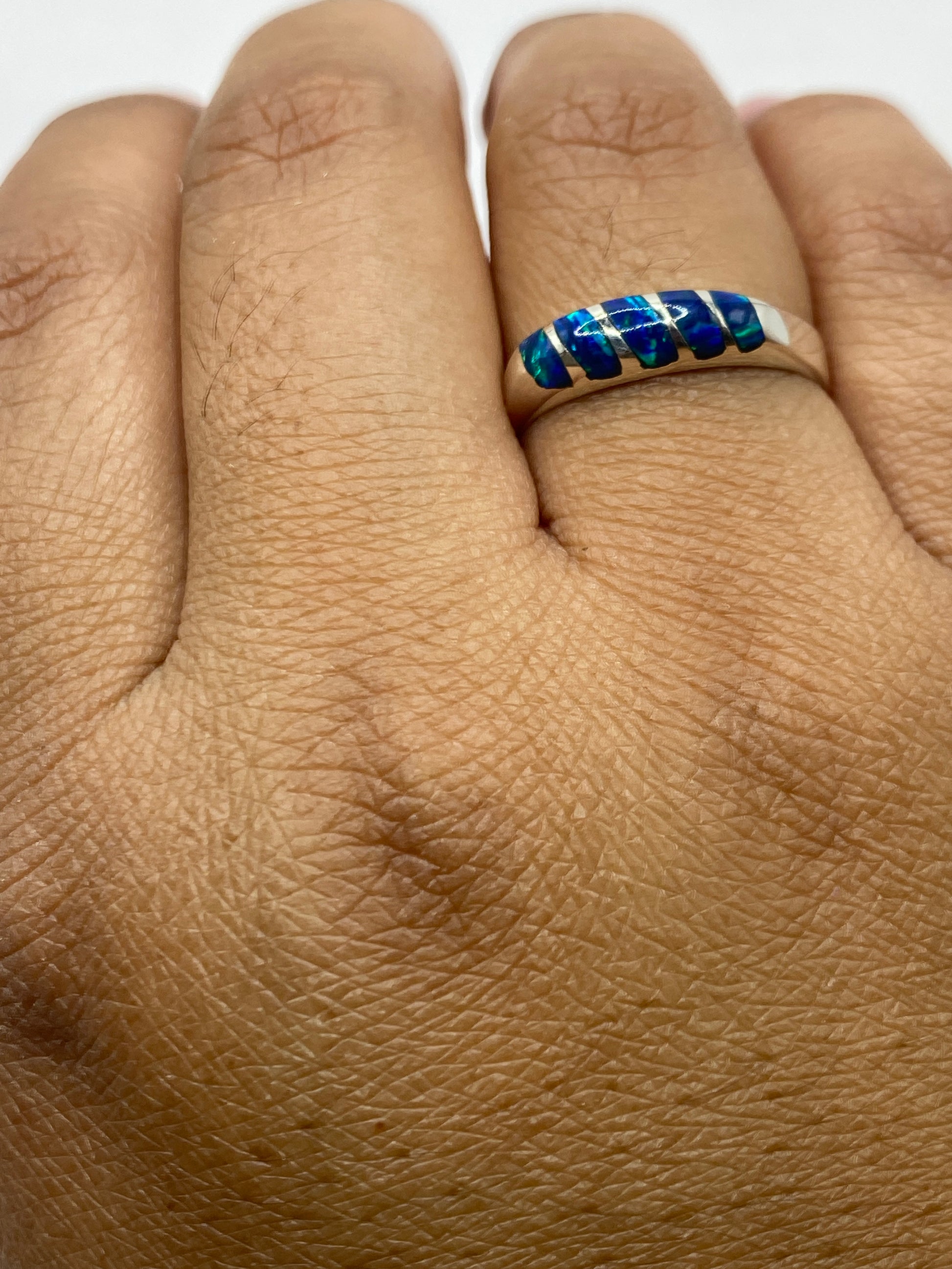 Anillo con ópalo azul puesto en dedo, vista con luz natural