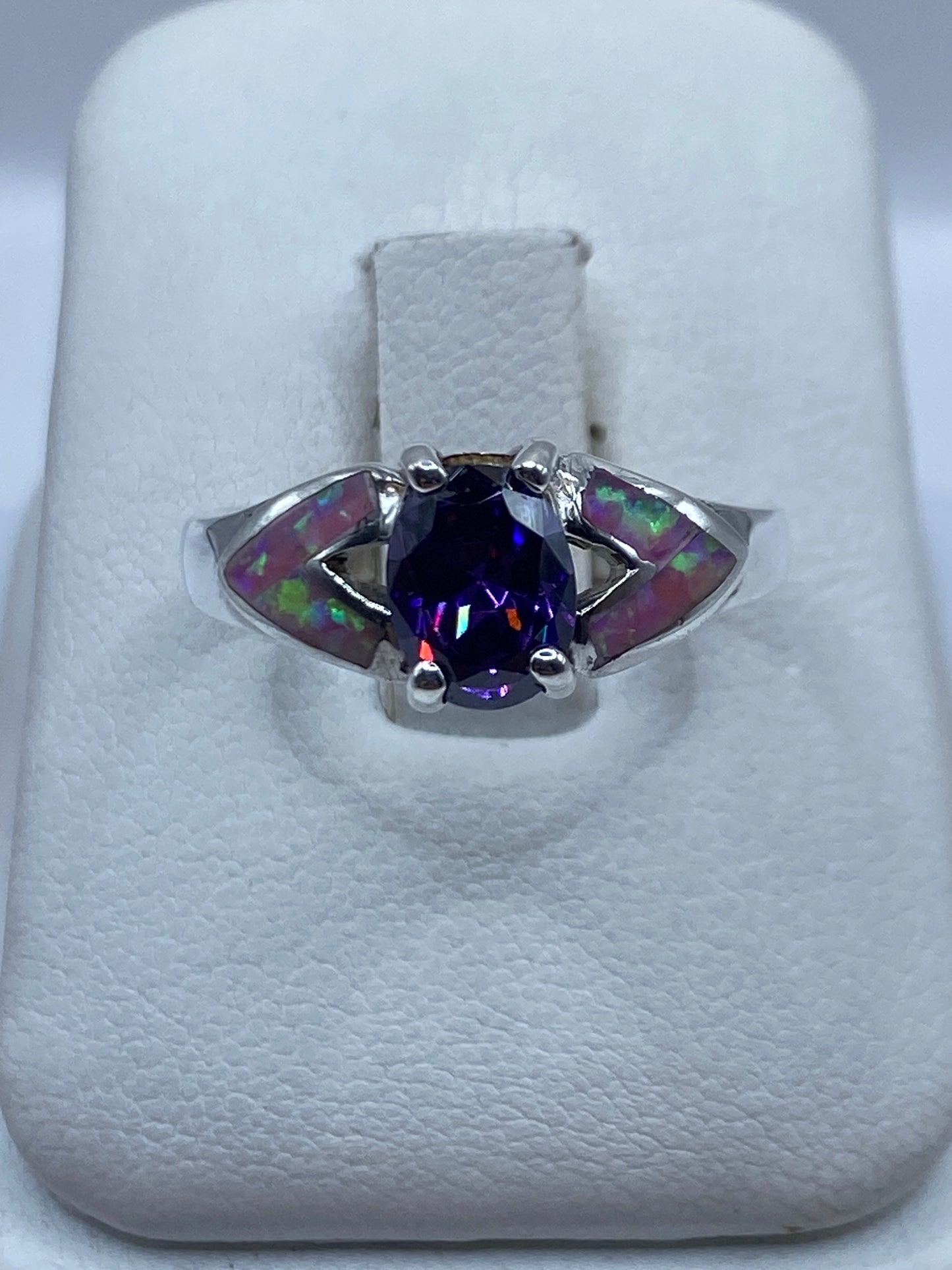 Anillo de plata con ópalo de fuego rosa en el dedo de una mujer, destellos naranja visibles