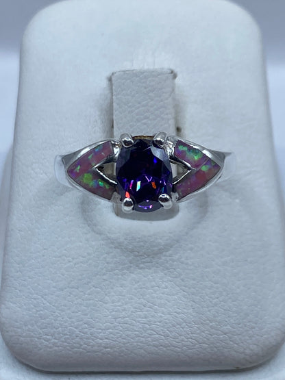Anillo de plata con ópalo de fuego rosa en el dedo de una mujer, destellos naranja visibles