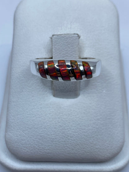 Anillo de plata .950 con ópalo de fuego multicolor en dedo de mujer, mostrando el juego de colores naranja y rojo