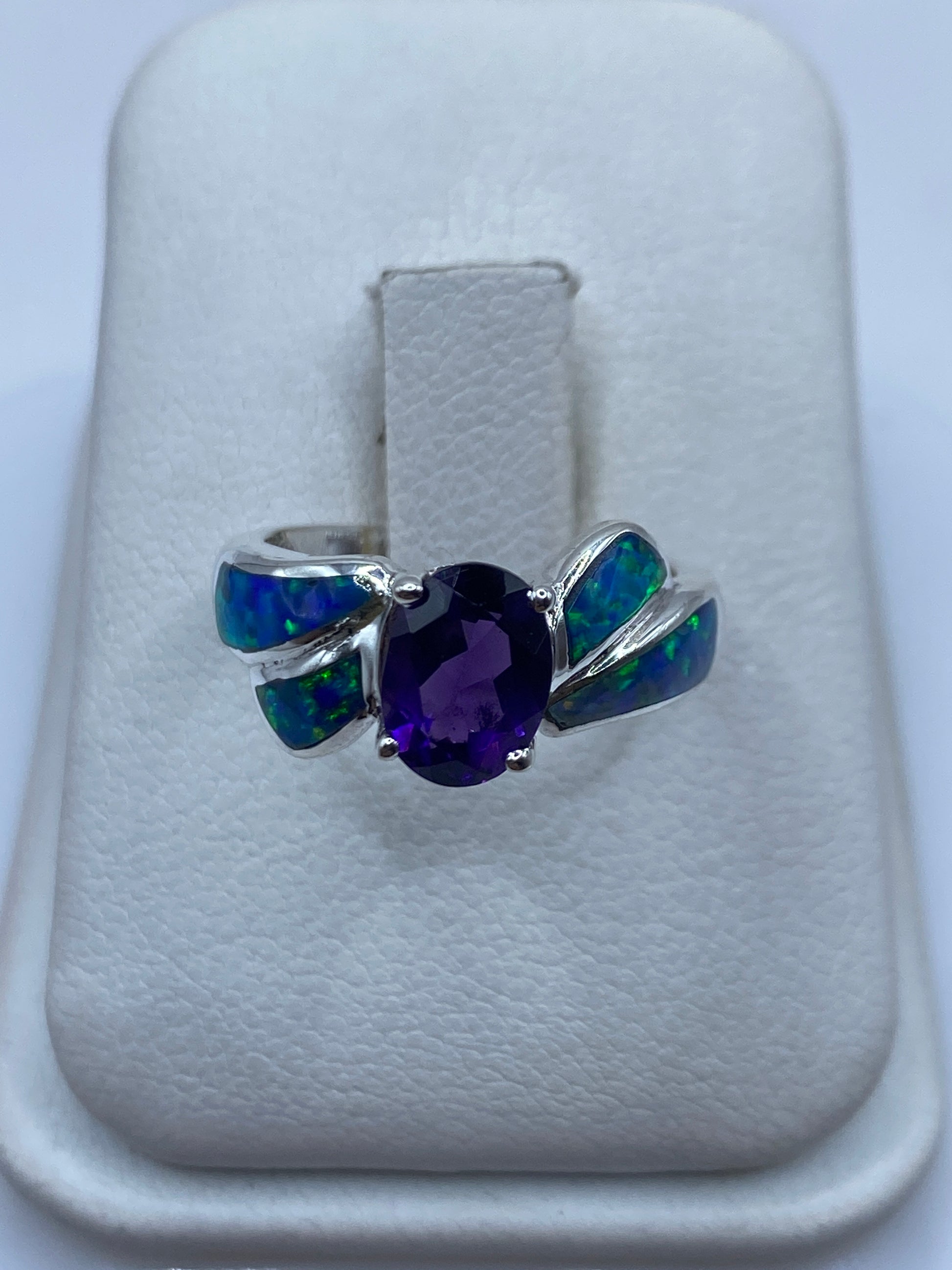 Anillo de plata con ópalo de fuego azul y alas asimétricas en la mano de una mujer