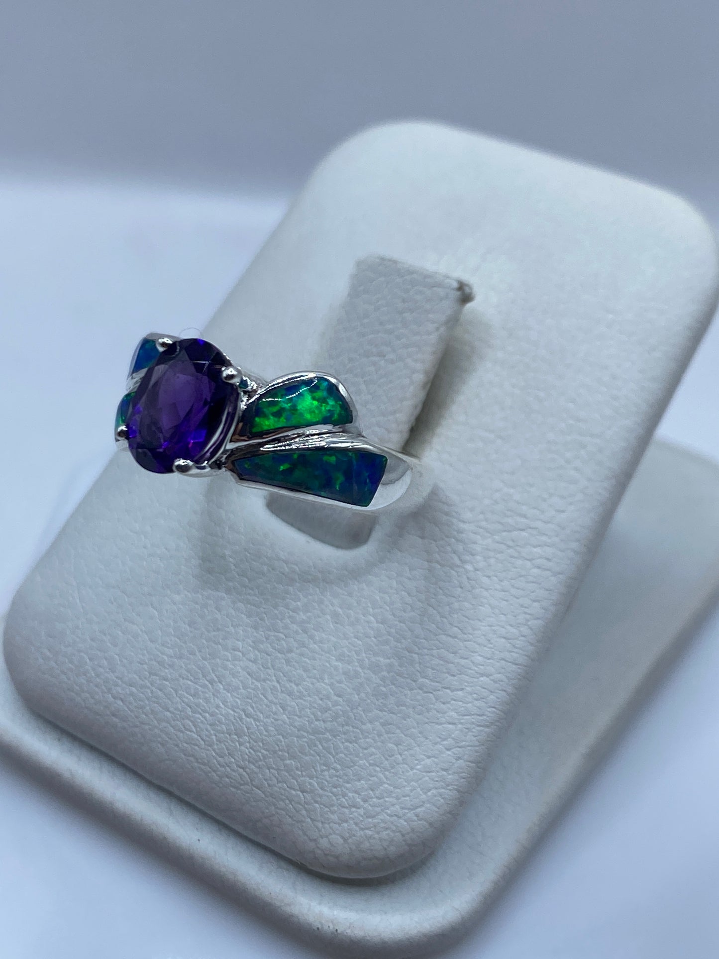 Vista lateral del anillo ópalo fuego destacando el diseño alado en plata pulida
