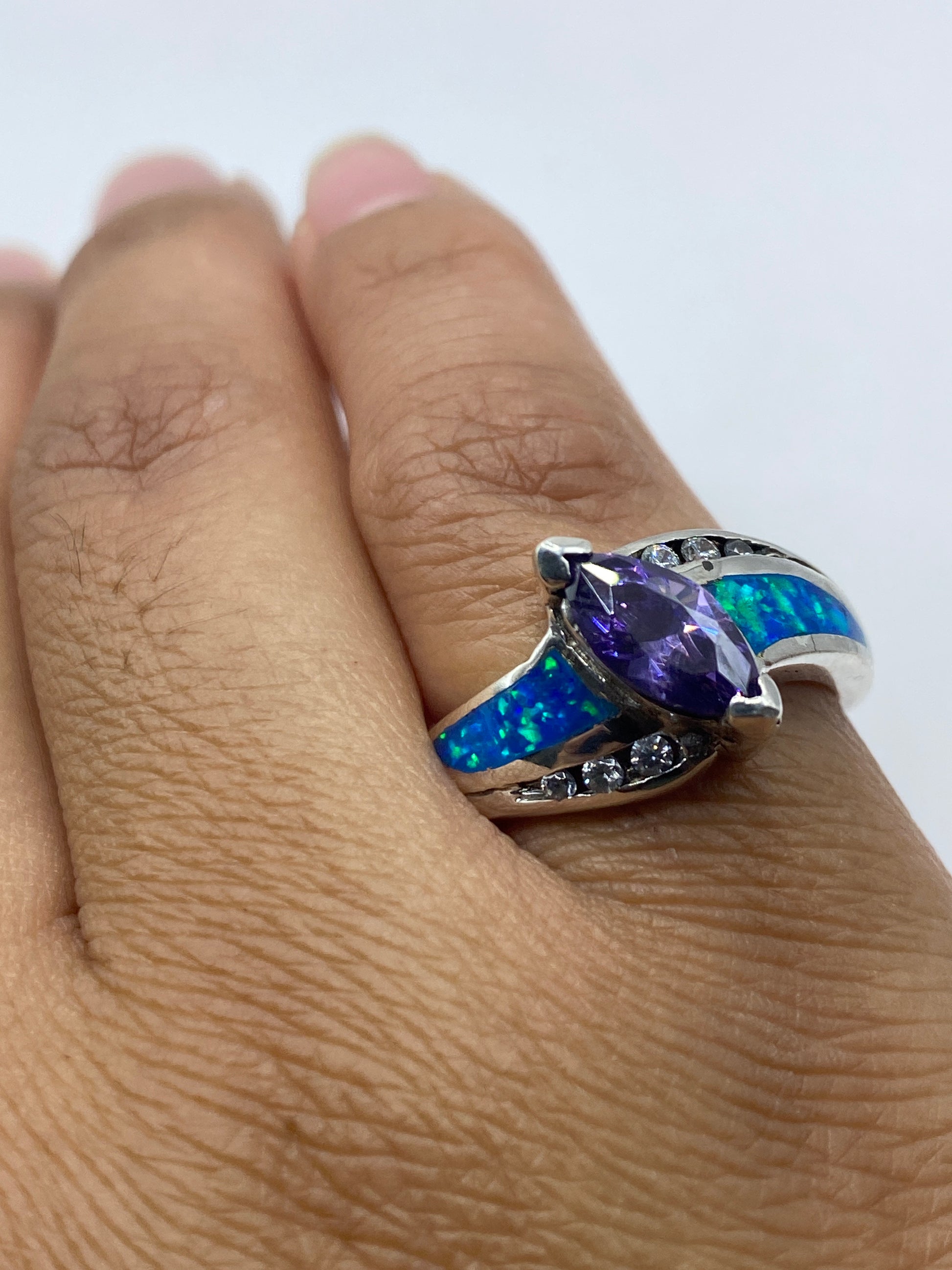 Anillo solitario con ópalo azul sobre fondo blanco, mostrando sello .925