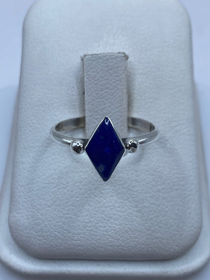 Anillo solitario de plata .950 con piedra azul engastada en el dedo anular