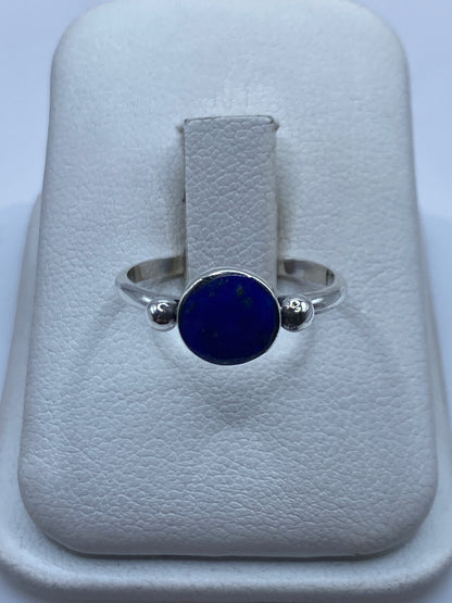 Anillo de plata con lapislázuli azul profundo sobre soporte blanco, vista frontal