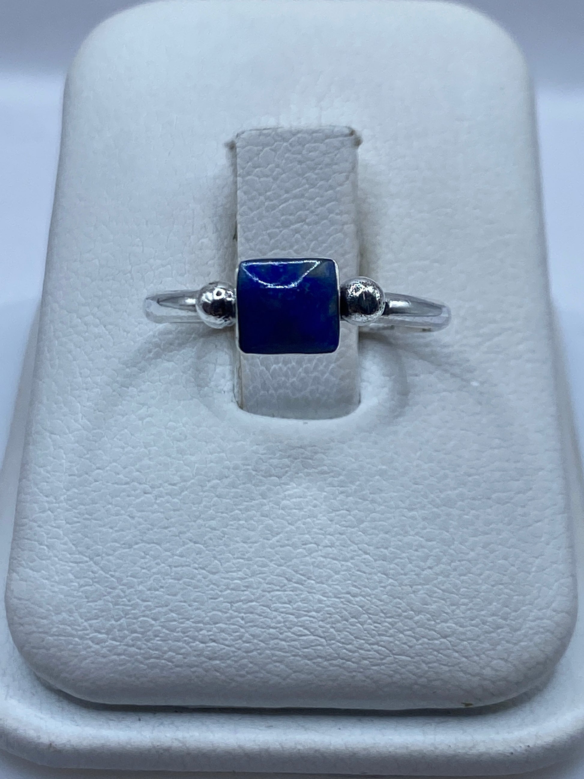 Anillo de plata .950 solitario con piedra azul cuadrada y esferas laterales, mostrado en estuche blanco