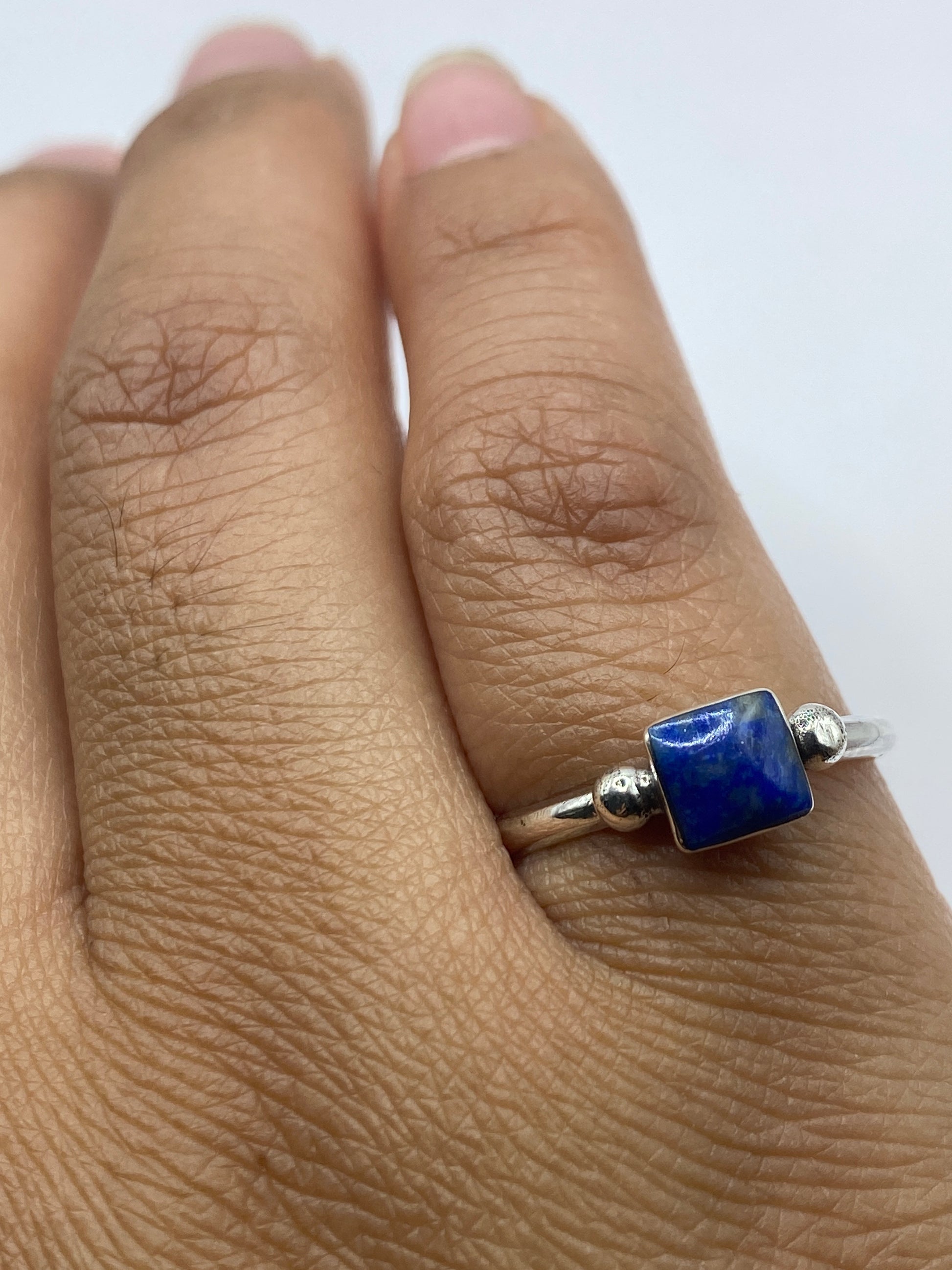 Anillo de plata con piedra azul sobre fondo gris, vista aérea del diseño completo