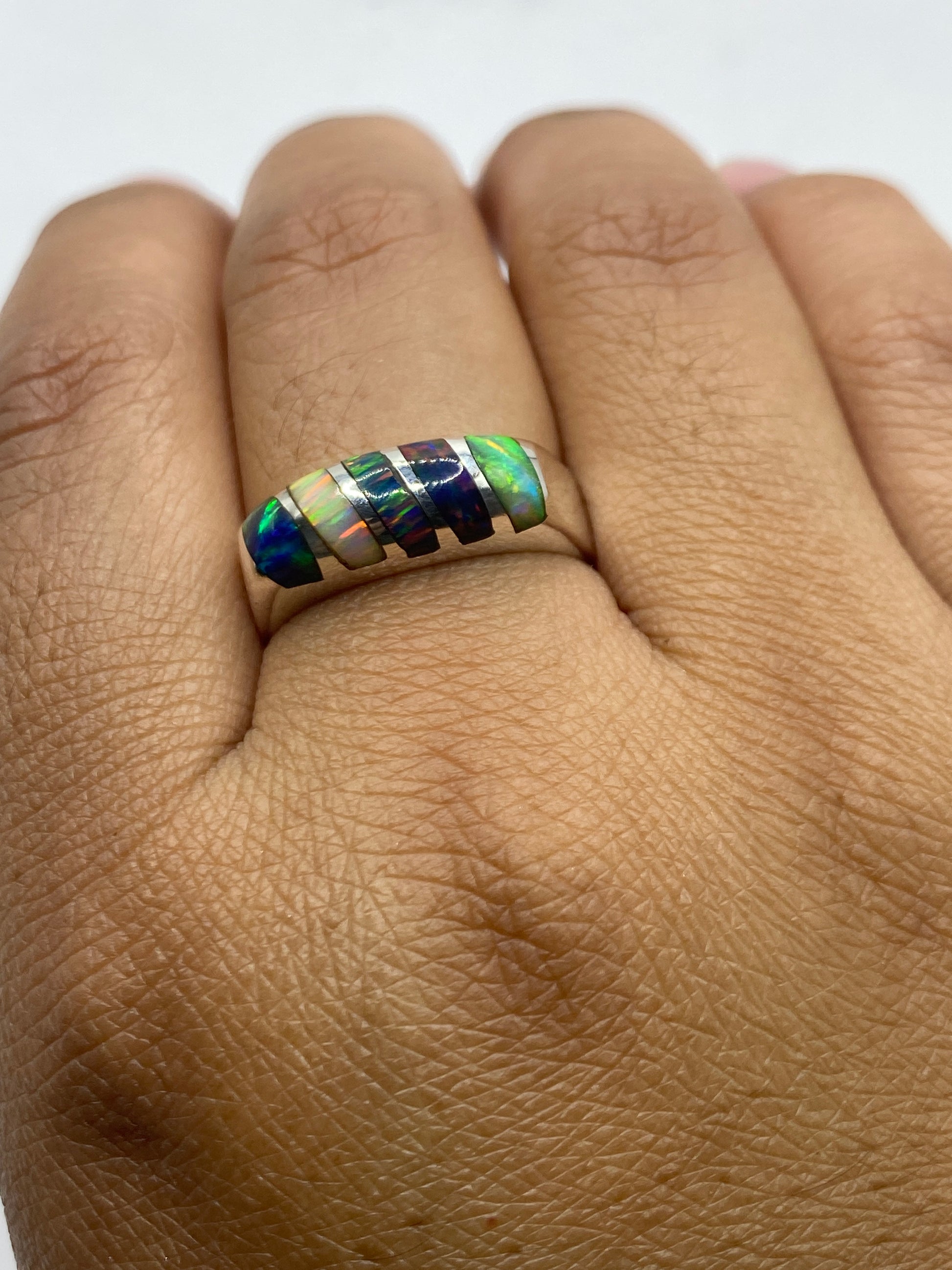 Anillo en la mano mostrando el juego de colores multicolor del ópalo con la luz