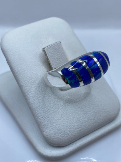 Vista frontal del anillo unisex mostrando el engaste de ópalo azul con juego cromático