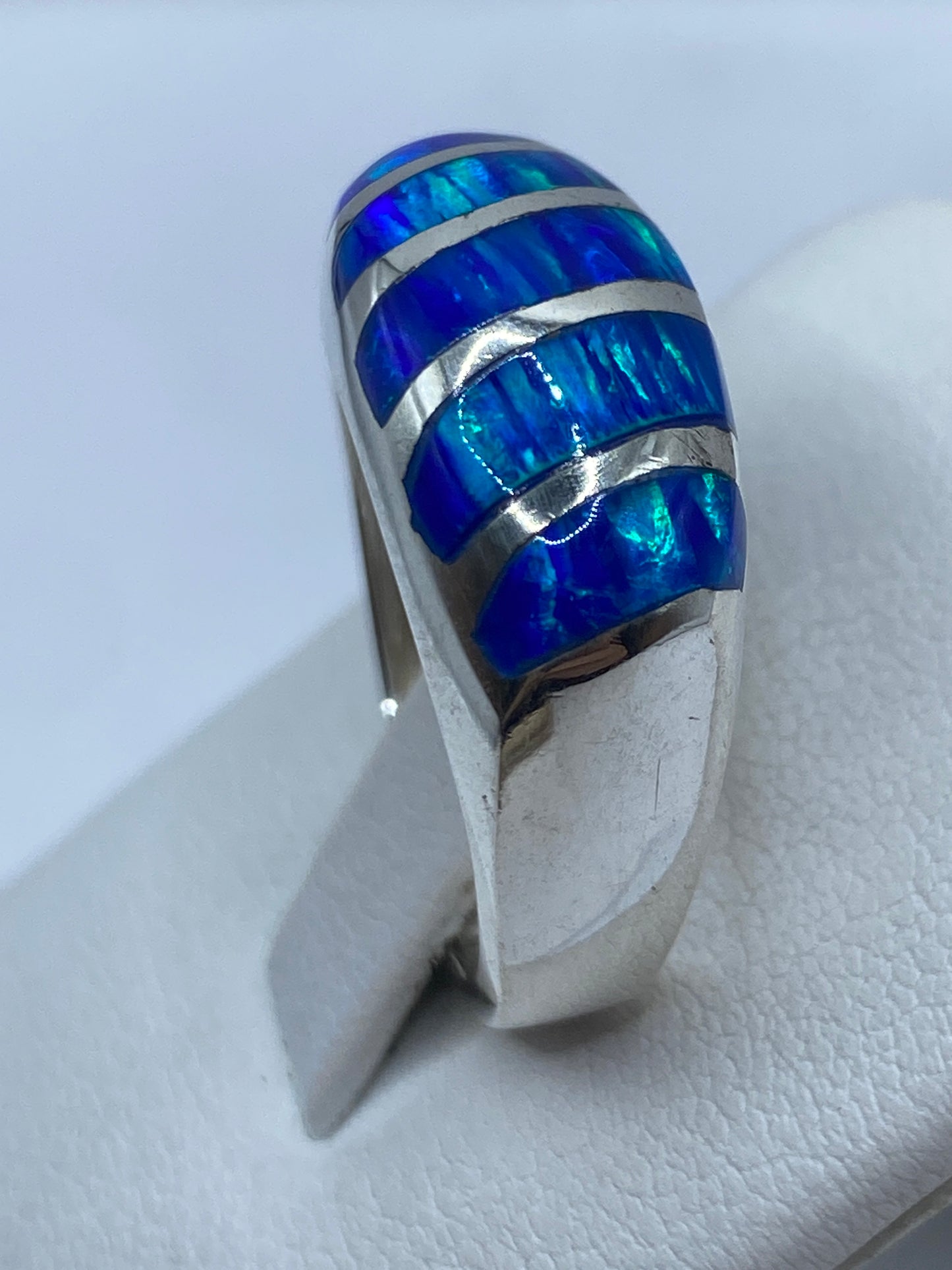Detalle lateral del anillo plata .950 con ópalo azul sobre dedo, iluminado naturalmente