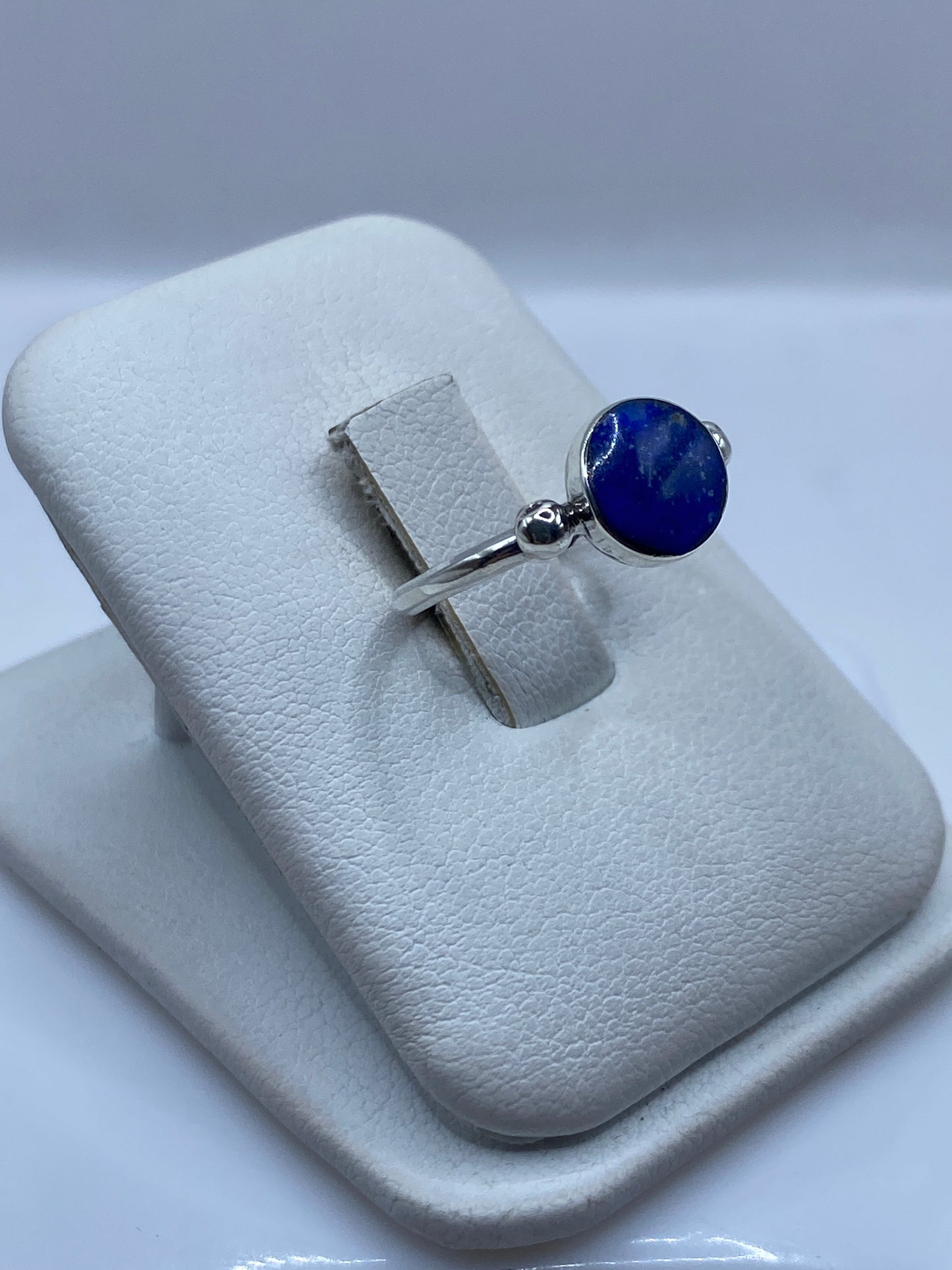Detalle lateral del anillo solitario mostrando volutas de plata y engaste de lapislázuli
