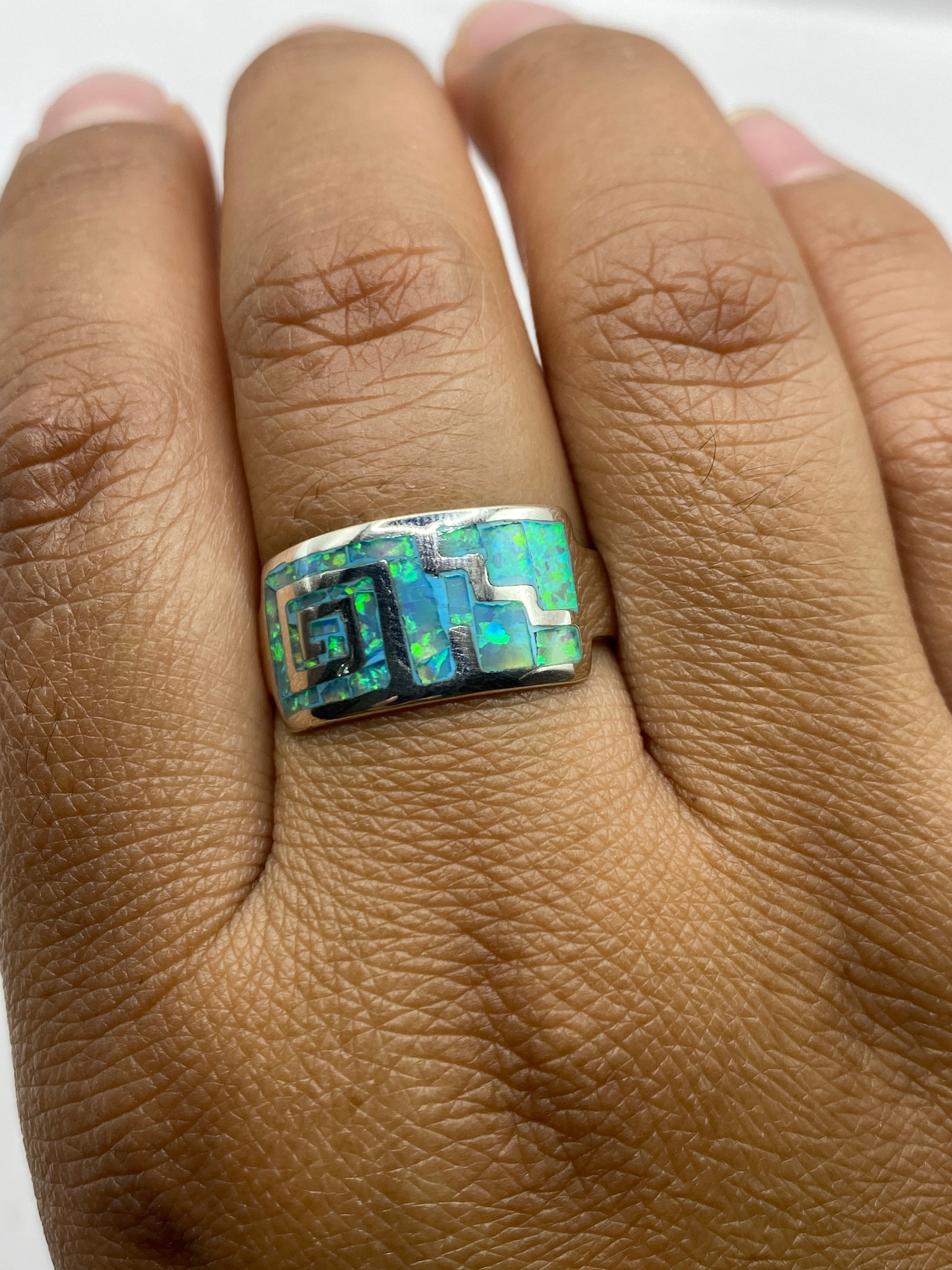 Anillo llevado en dedo mostrando el fuego natural azul-verde del ópalo