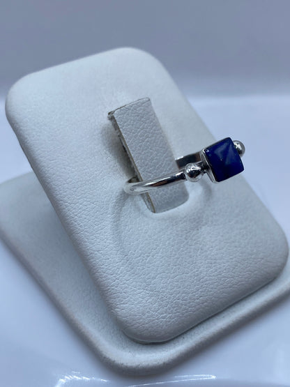 Vista frontal del anillo minimalista con piedra azul en mano de mujer