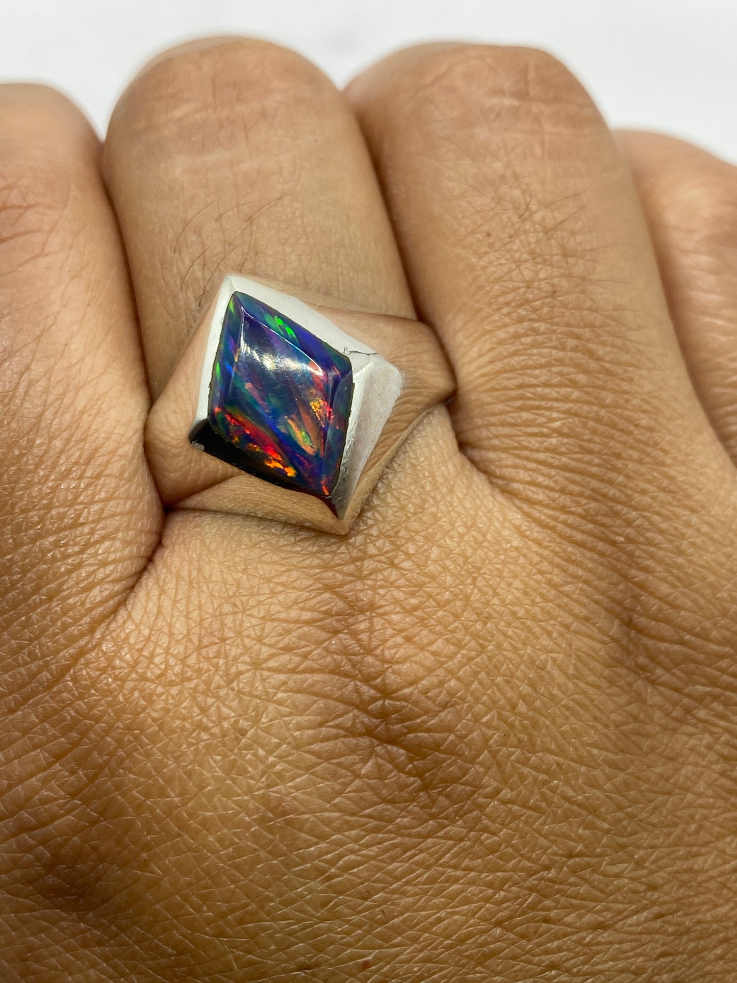 Anillo en mano de hombre mostrando presencia y juego de luces del ópalo multicolor