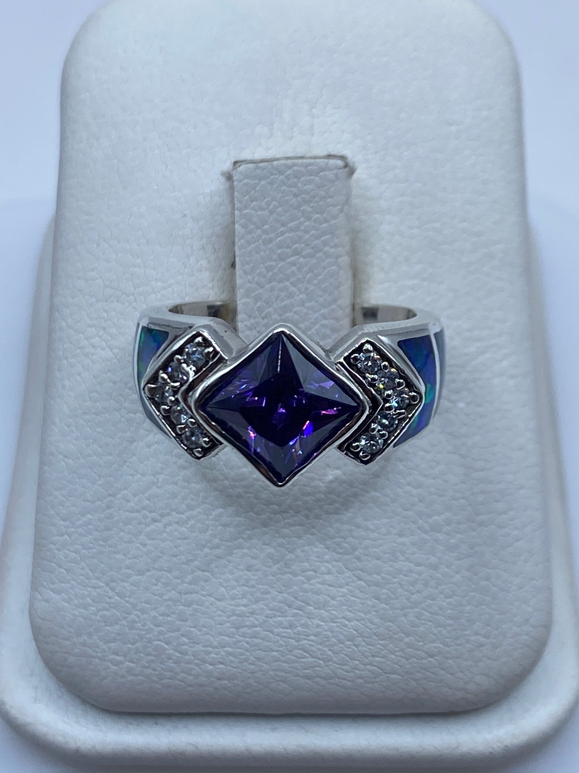 Anillo de plata con ópalo de fuego multicolor y circonias sobre papel blanco