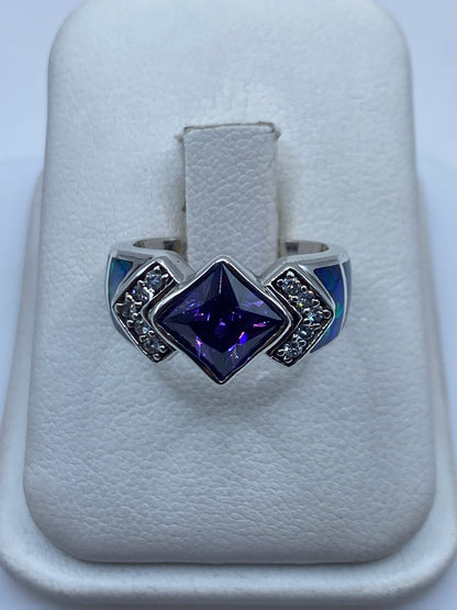 Anillo de plata con ópalo de fuego multicolor y circonias sobre papel blanco