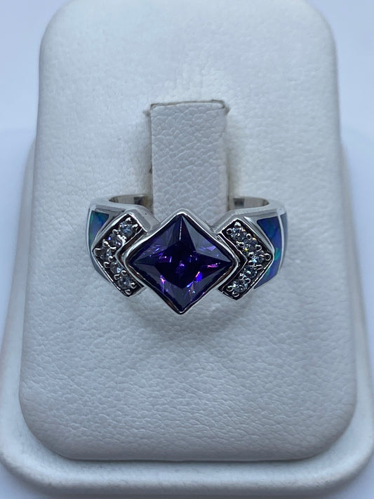 Anillo de plata con ópalo de fuego multicolor y circonias sobre papel blanco